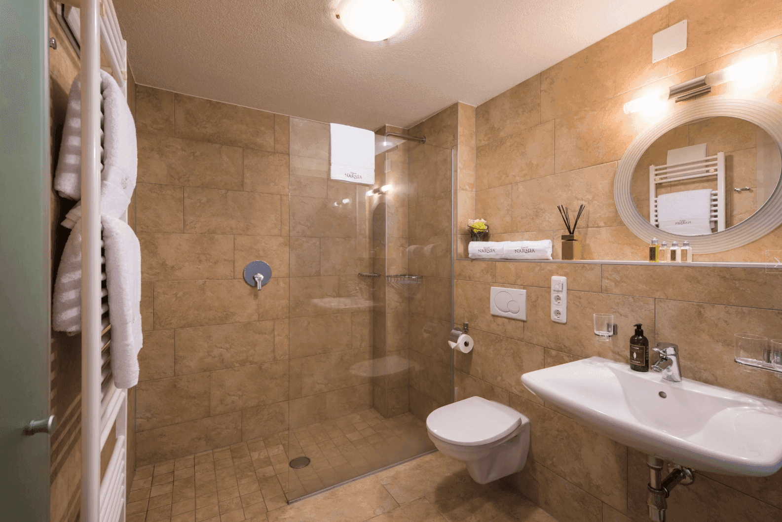 Modernes Badezimmer mit ebenerdiger Dusche, Einzelwaschbecken und rundem Spiegel.