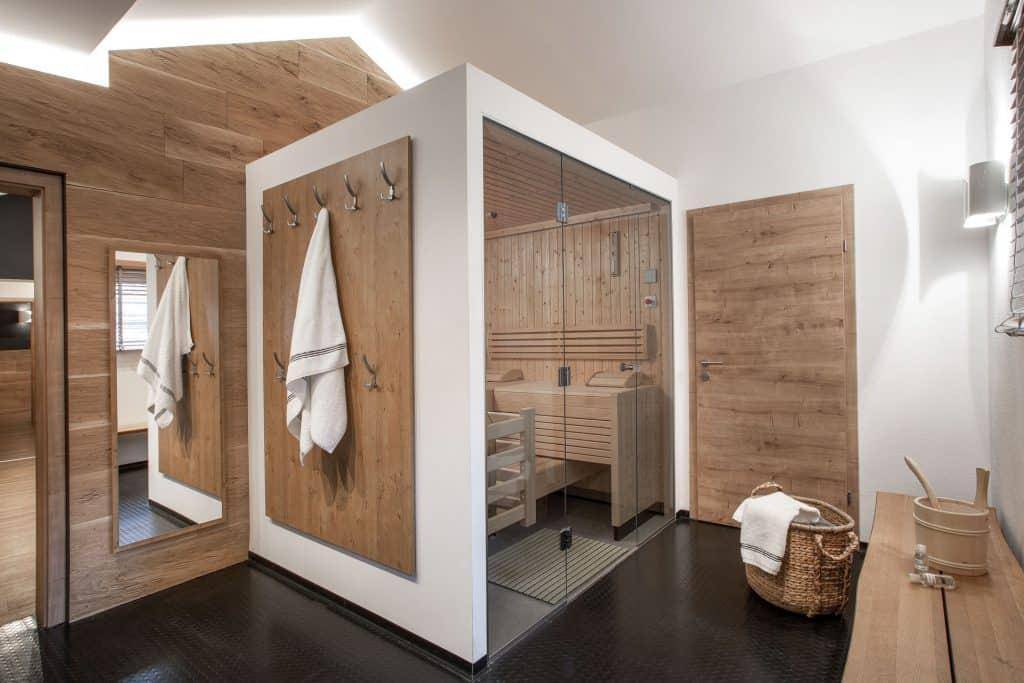 Moderner Wellnessbereich mit integrierter Sauna, Holzelementen und dunklem Fliesenboden.