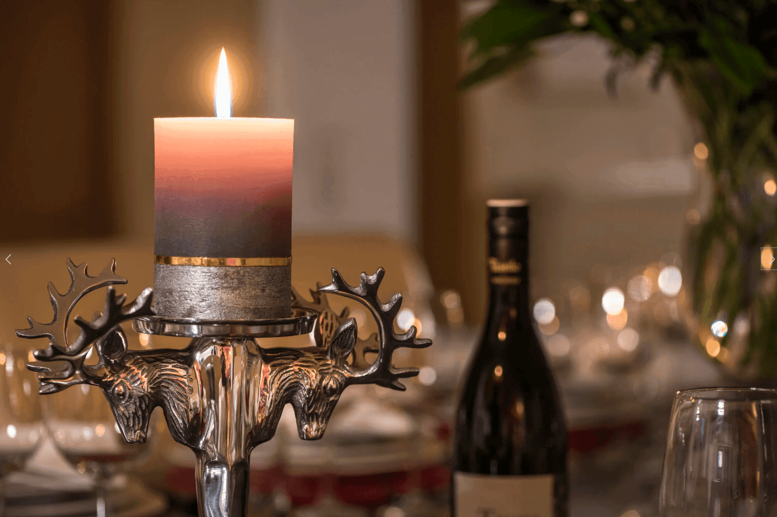 Stimmungsvolle Kerze in einem Hirschgeweih-Kerzenhalter auf einem festlich gedeckten Tisch.