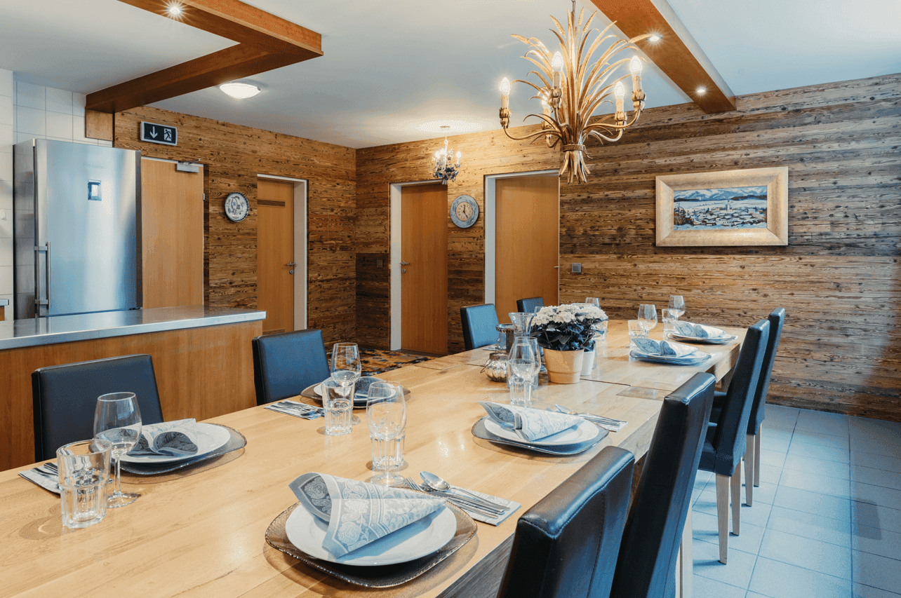Großer Essbereich mit langer Holztafel, stilvoller Beleuchtung und Holzwänden.