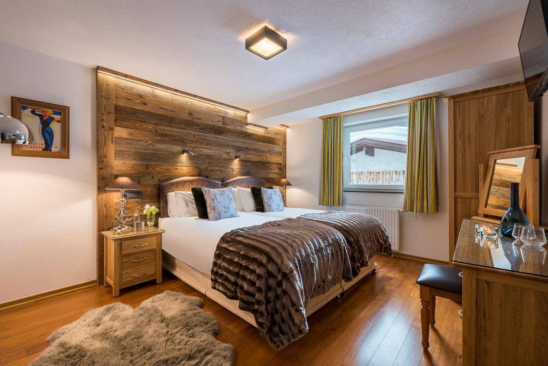 Gemütliches Schlafzimmer mit Holzboden, Schminktisch und Fensterblick auf die Umgebung.