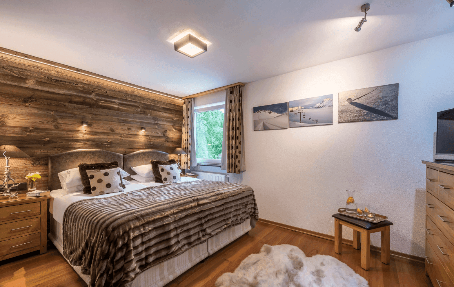 Gemütliches Schlafzimmer im alpinen Stil mit Holzwand, Doppelbett und Holzboden.