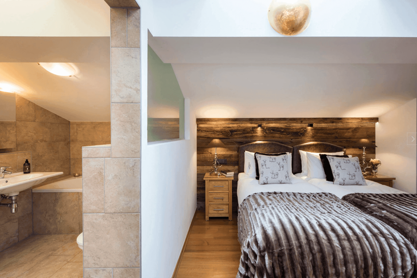 Schlafzimmer mit Holzboden und direktem Zugang zu einem modernen Badezimmer.