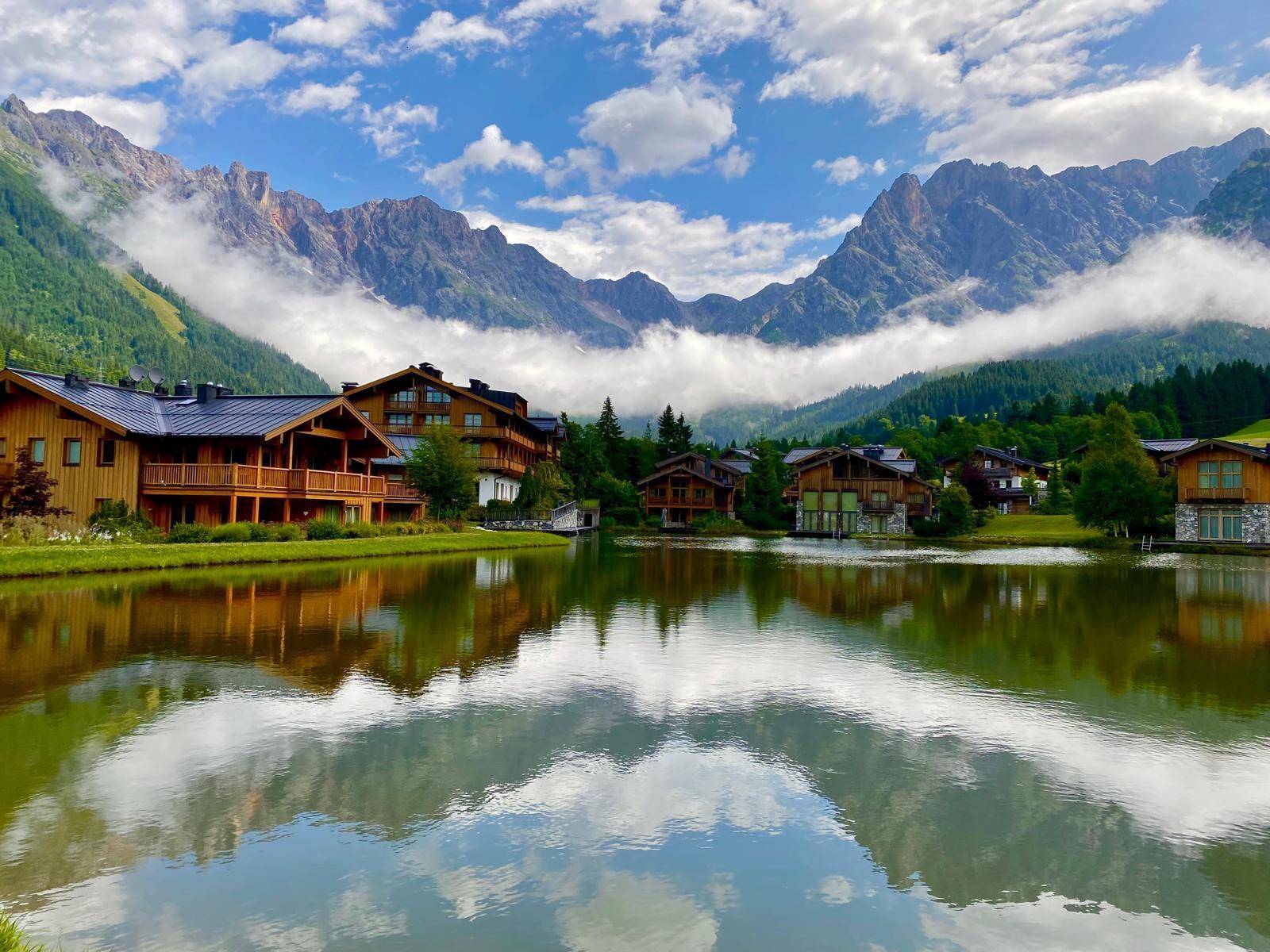 Malerisches Dorf am Seeufer mit traditionellen Holzhäusern und majestätischen Bergen im Hintergrund.