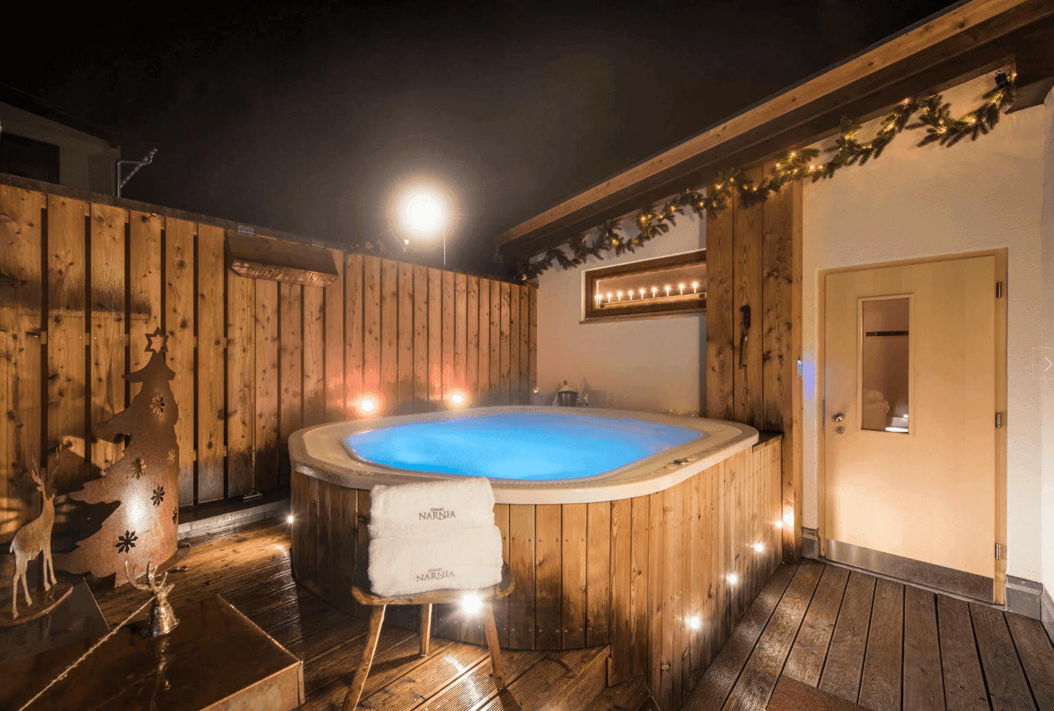 Gemütlicher Außenbereich mit Whirlpool, Holzverkleidung und festlicher Weihnachtsdekoration.