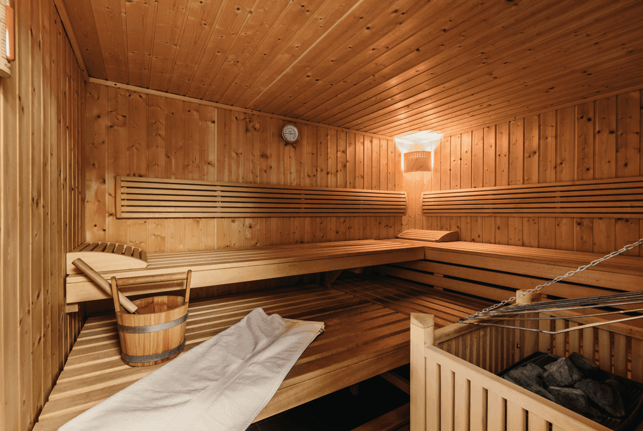 Geräumige Holzsauna mit mehreren Bänken und traditionellem Saunaofen für Entspannung.