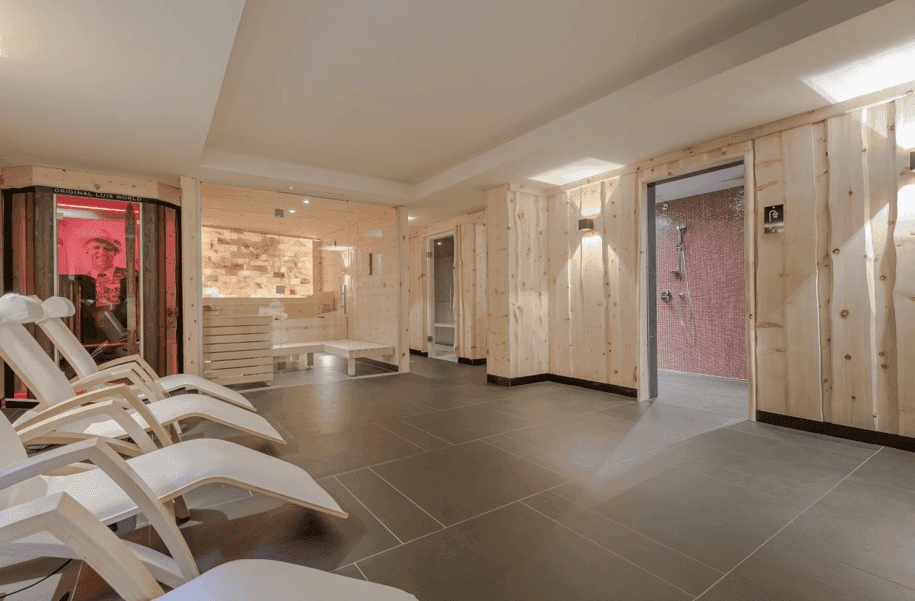 Geräumiger Wellnessbereich mit Liegestühlen, Sauna und Duschkabinen für Erholung.