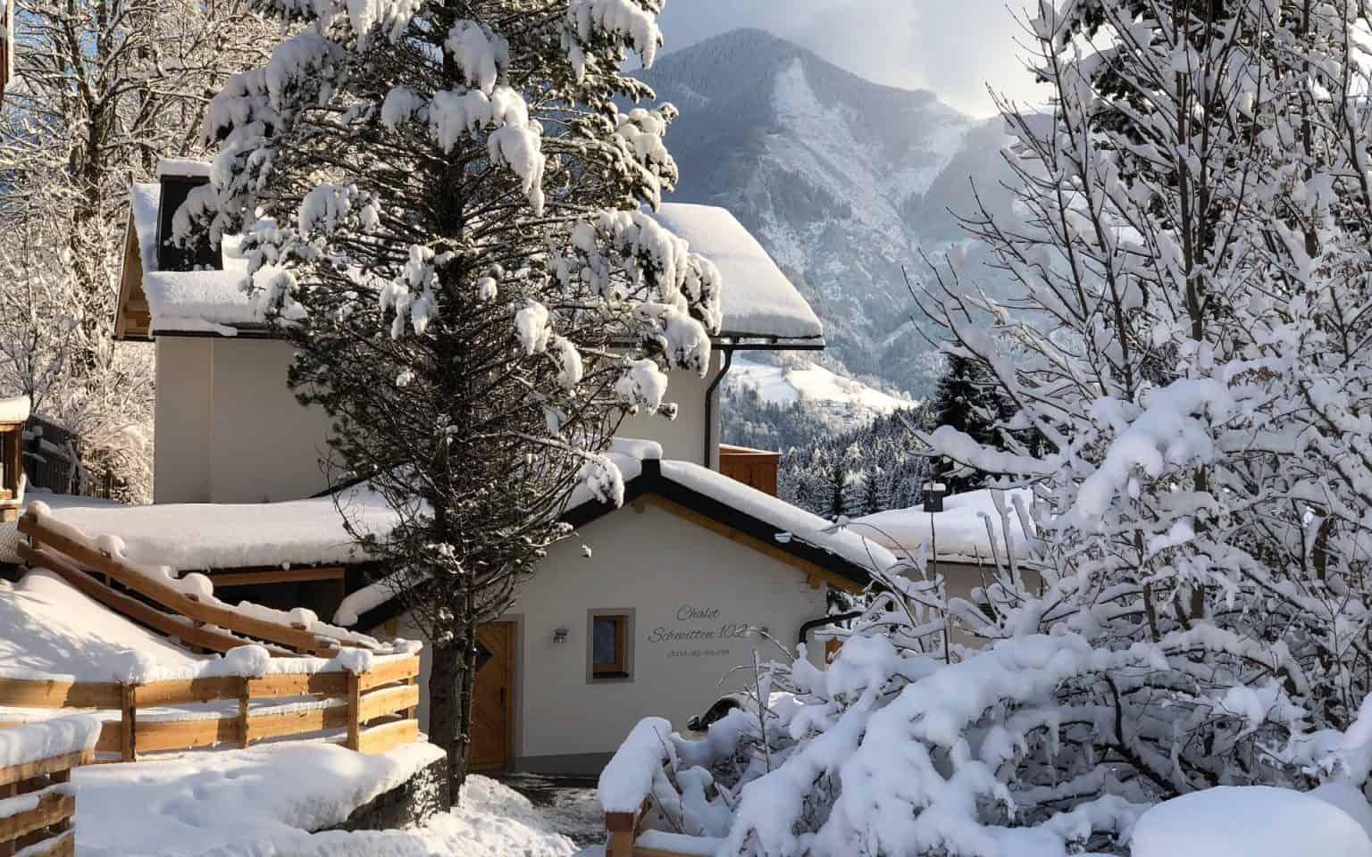 Idyllisches Haus im Winterwunderland, umgeben von verschneiten Bäumen und Bergen.