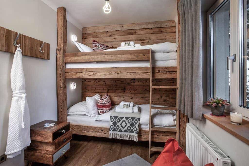 Kinderfreundliches Schlafzimmer mit rustikalen Holz-Etagenbetten und Blick ins Grüne.