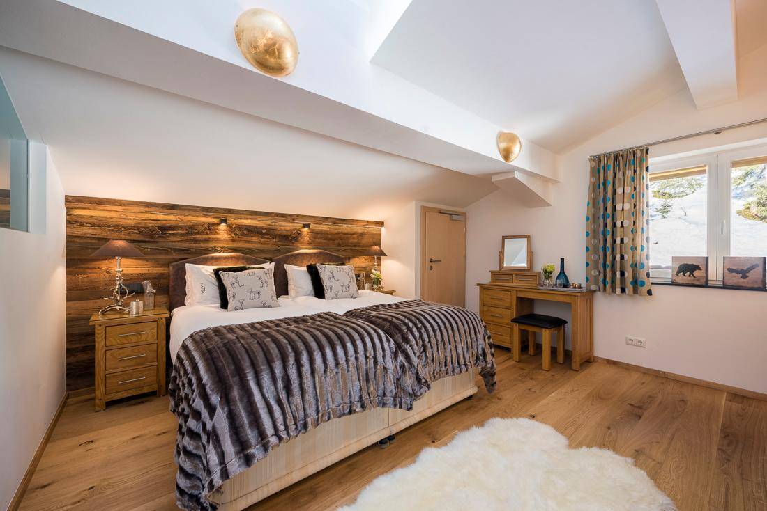 Geräumiges Schlafzimmer mit Holzboden, Schminktisch und Fensterblick auf die verschneite Landschaft.