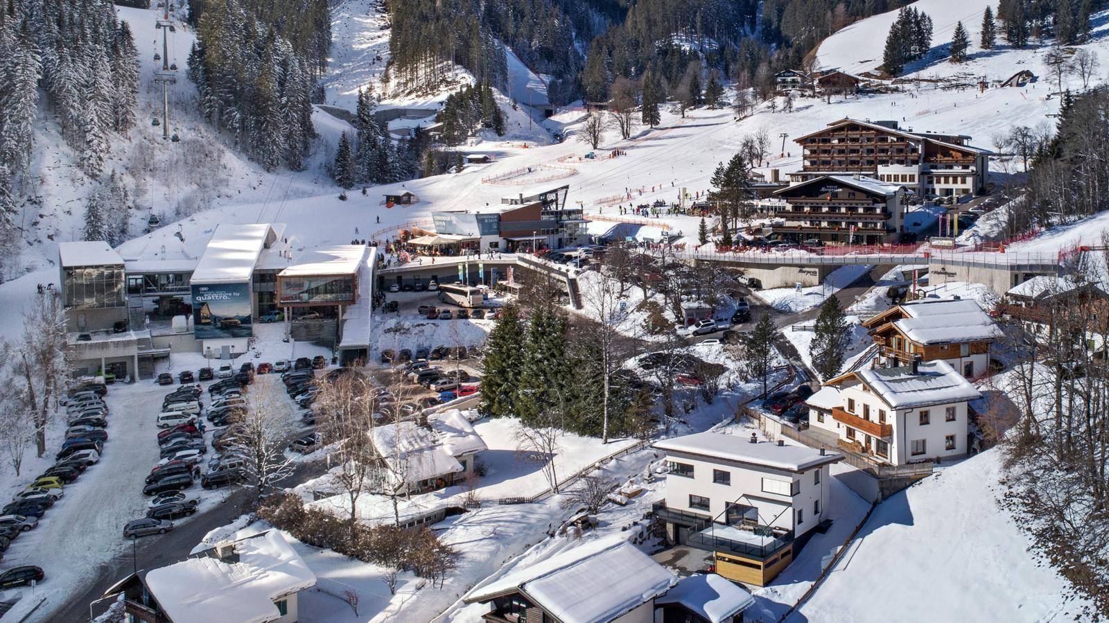 Weitläufige Ansicht eines Skigebiets mit mehreren Gebäuden und verschneiten Pisten.