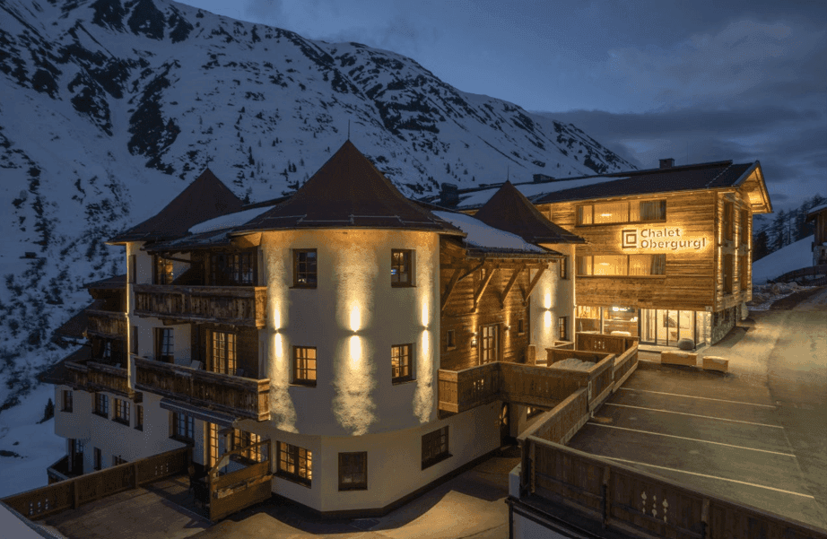 Großzügiges Chalet-Resort mit traditioneller Architektur und beleuchteter Fassade in den Bergen.