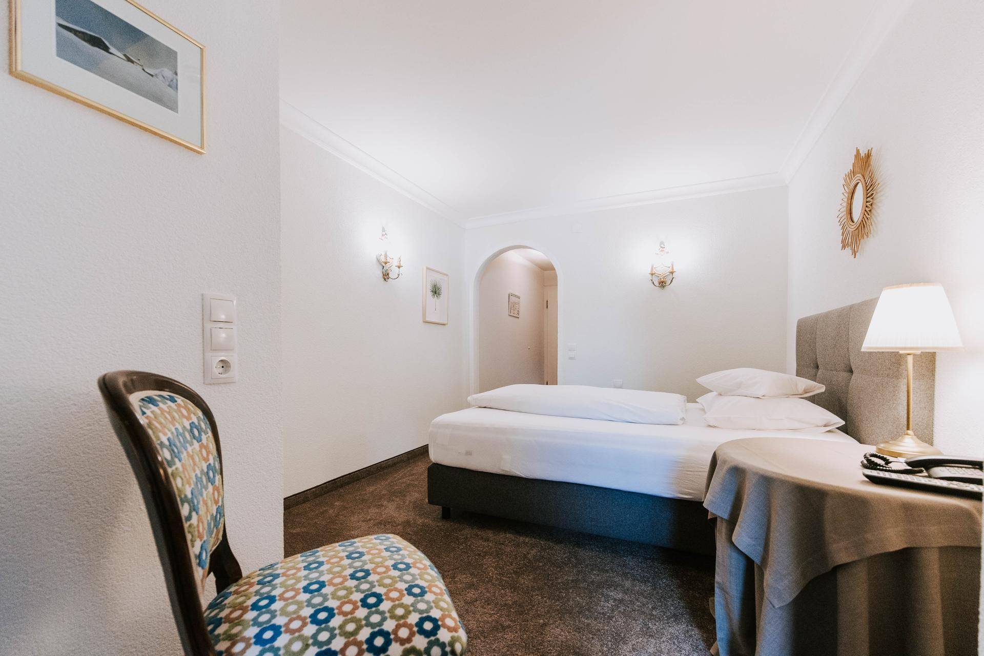 Gemütliches Schlafzimmer mit Einzelbett, Teppichboden und klassischer Einrichtung.