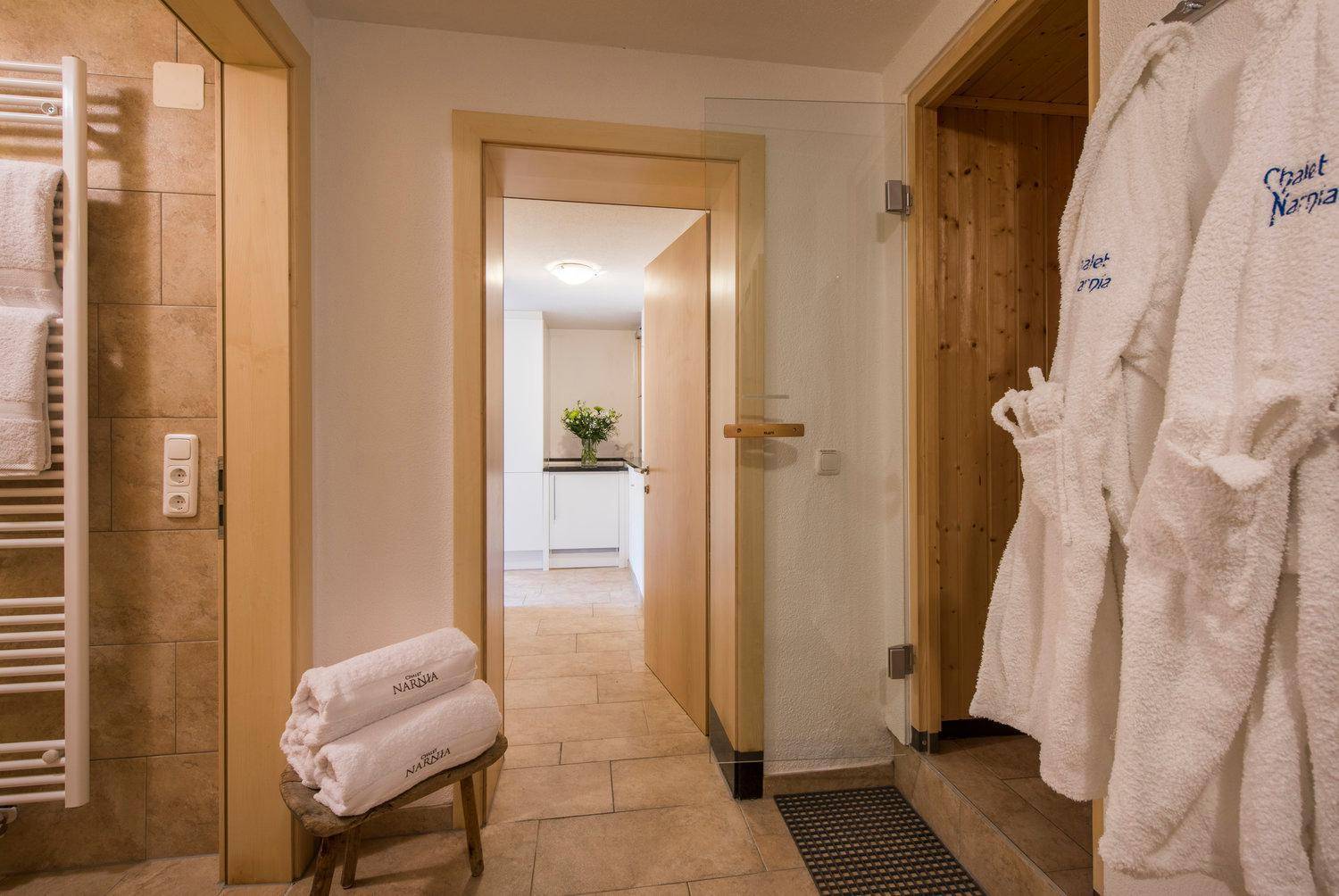 Flur mit Fliesenboden, Handtuchhalter und Zugang zu Sauna und weiteren Räumen.