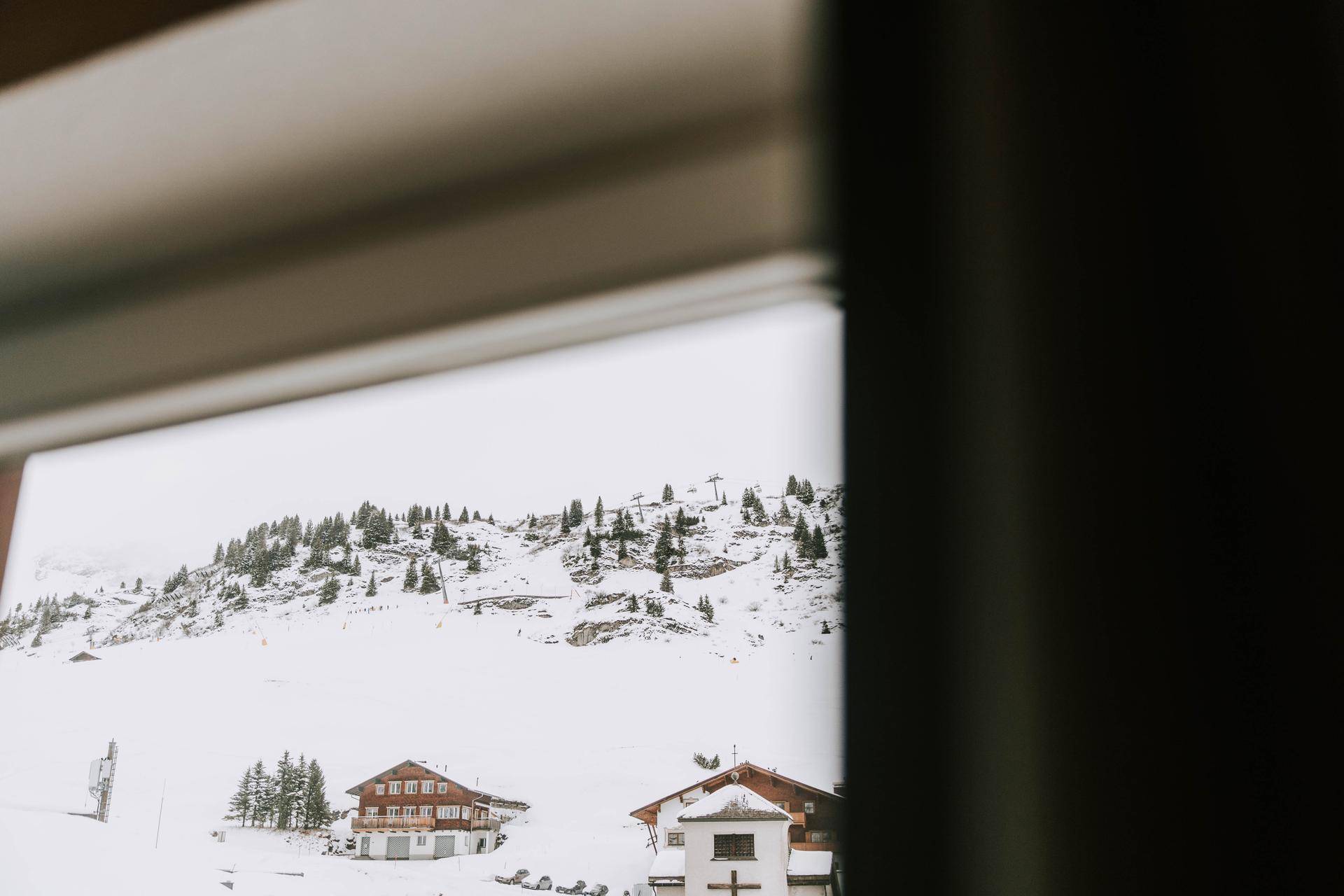 Blick aus dem Fenster auf die verschneite Berglandschaft mit traditionellen Häusern.