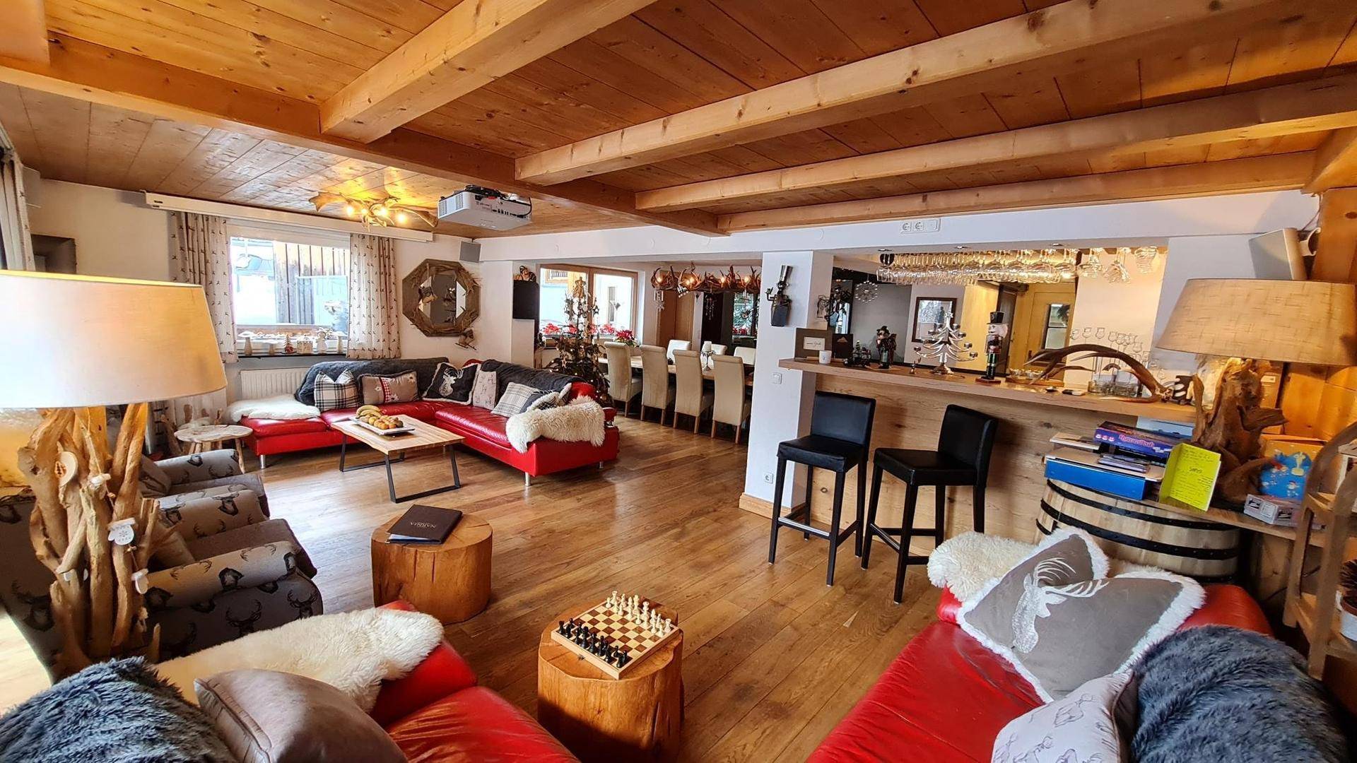 Gemütliches Wohnzimmer mit Holzbalkendecke, roten Sofas und traditioneller Einrichtung.