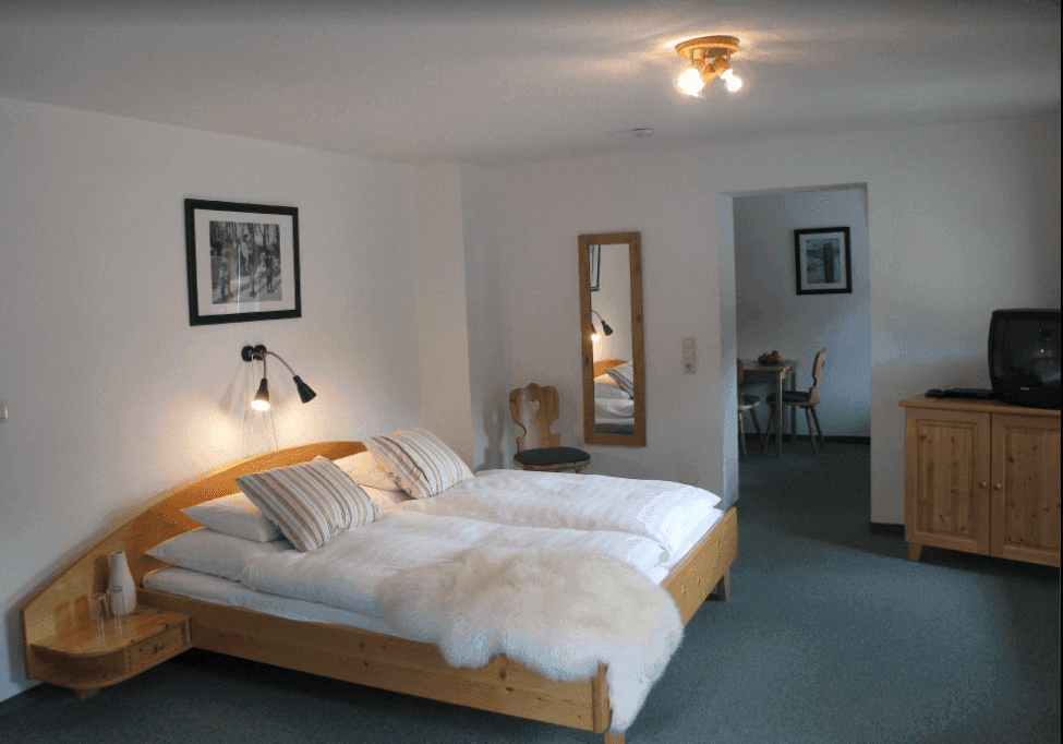Gemütliches Schlafzimmer mit Doppelbett, Teppichboden und Blick in einen angrenzenden Raum.