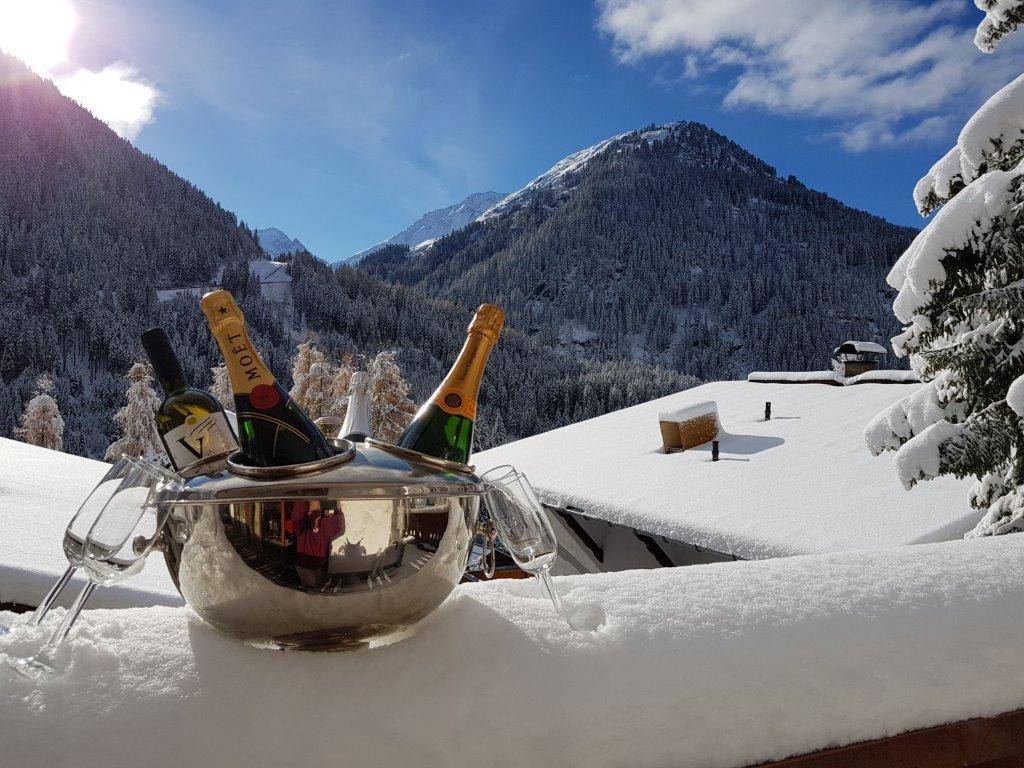 Champagner auf einem schneebedeckten Dach mit atemberaubendem Blick auf die winterliche Bergwelt.