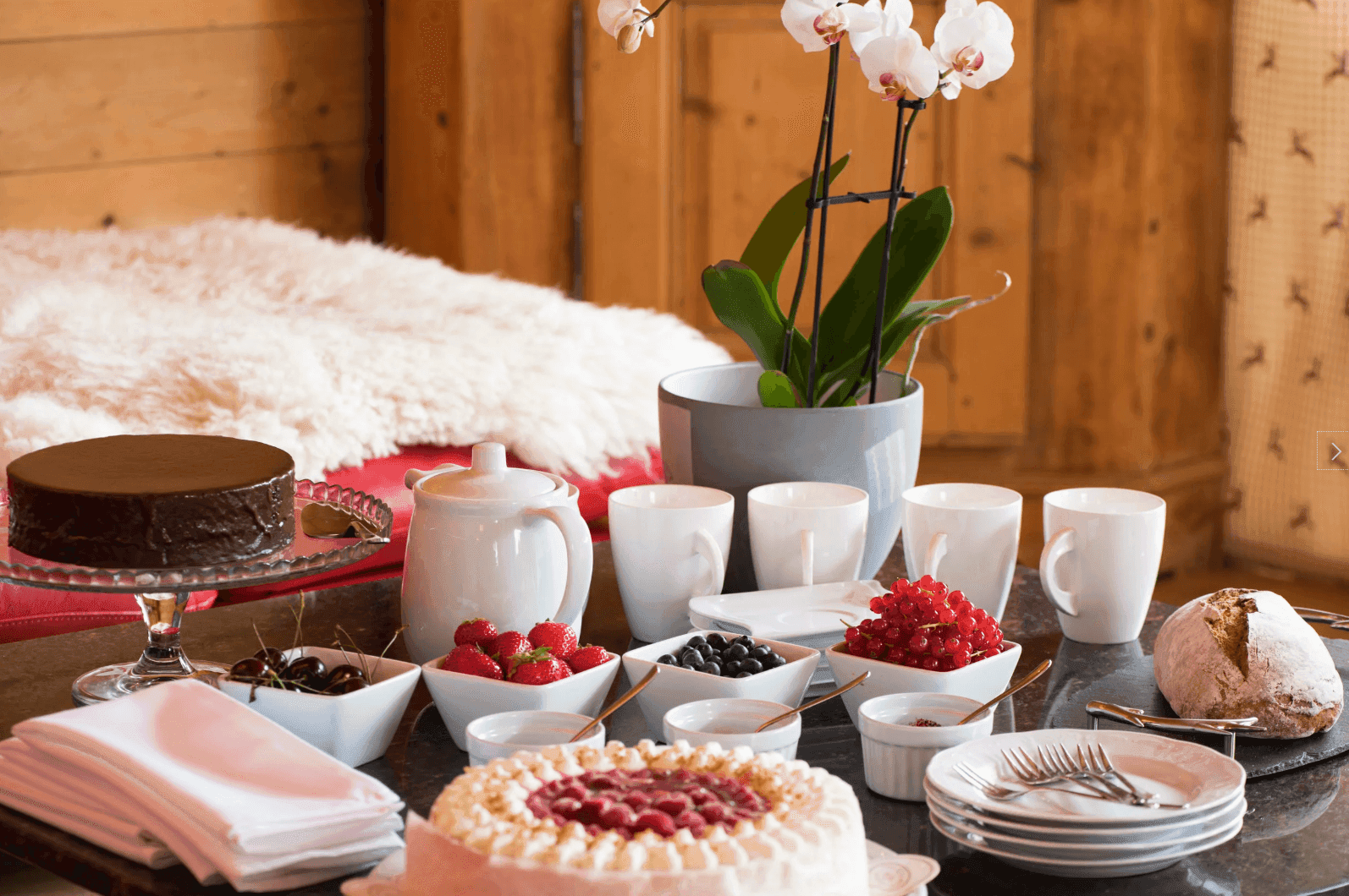 Festlich gedeckter Tisch mit Kuchen, Beeren und Kaffee, umgeben von traditioneller Holzvertäfelung.