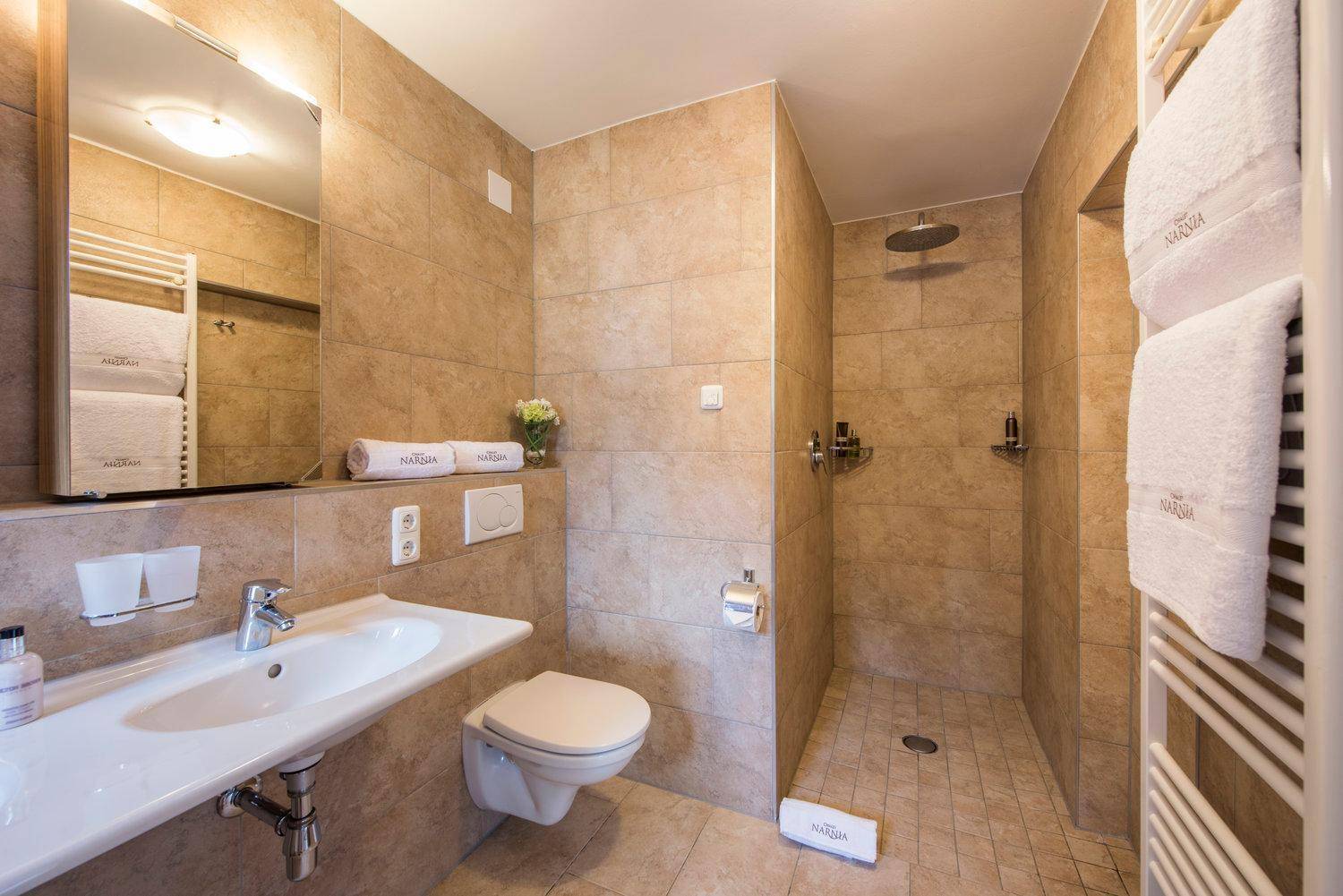Modernes Badezimmer mit ebenerdiger Dusche, Einzelwaschbecken und beheiztem Handtuchhalter.