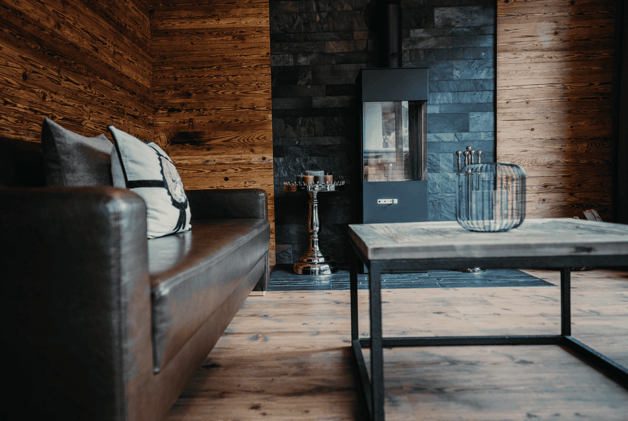 Detailansicht des Wohnzimmers mit Ledersofa, Holztisch und modernem Kaminofen.