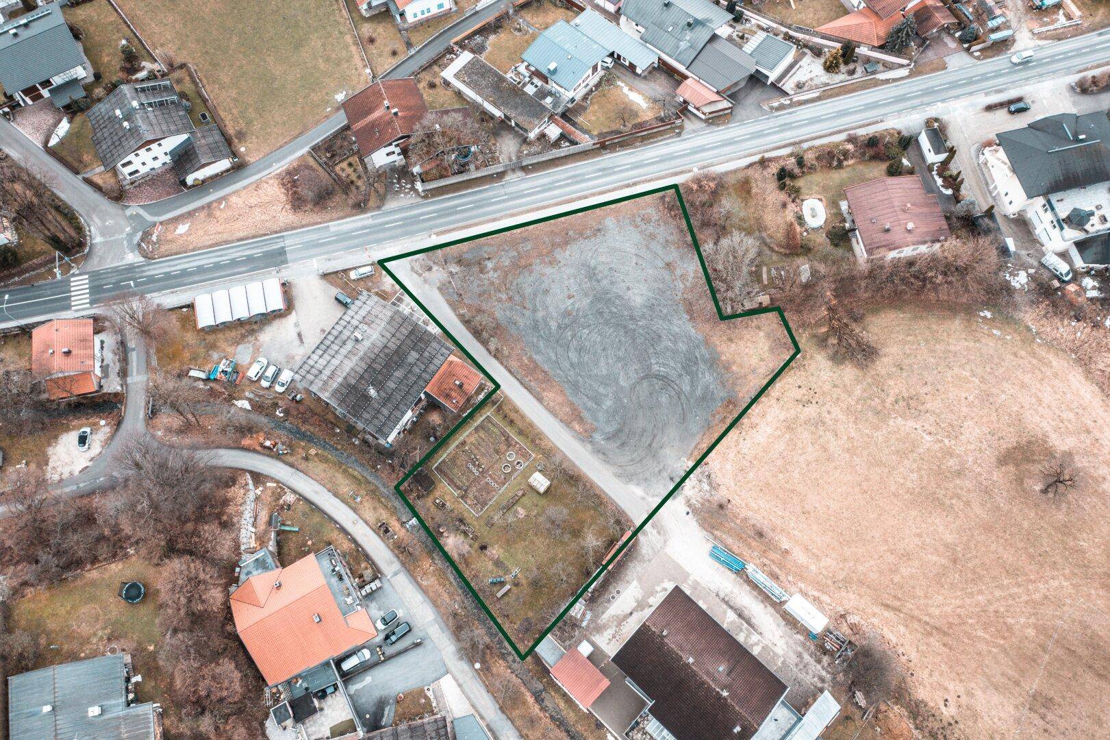Luftaufnahme eines Grundstücks mit grüner Umrandung, umgeben von Straßen und Häusern in ländlicher Umgebung.