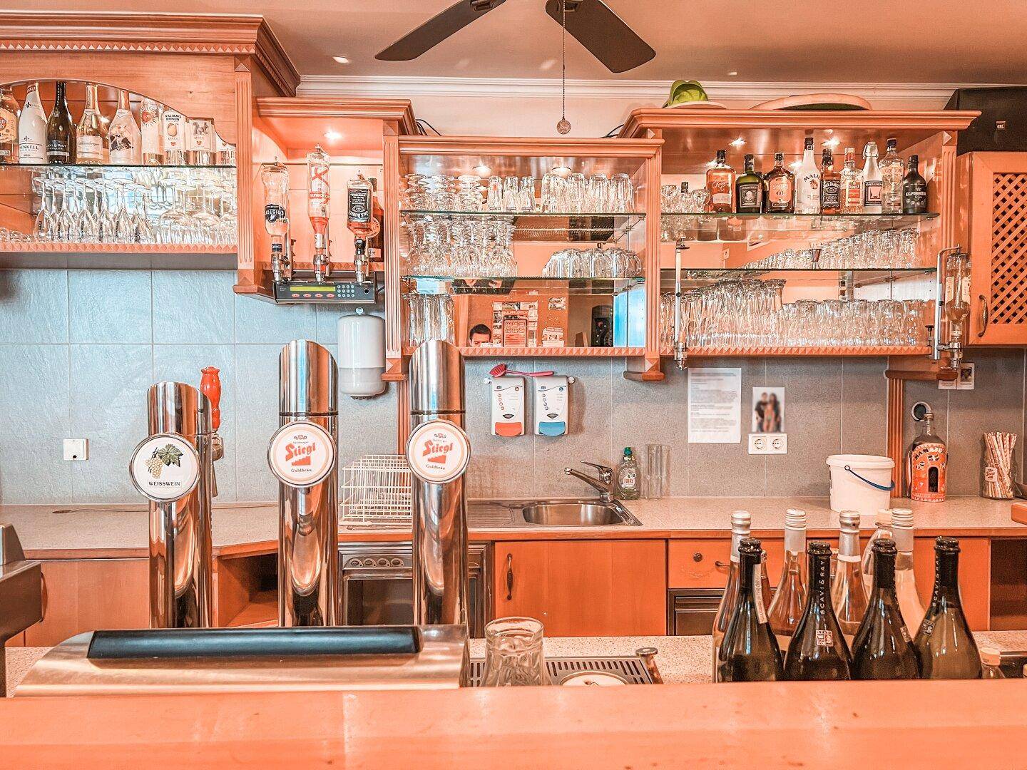 Detailansicht der Bar mit Zapfanlagen, Gläsern und Flaschen, bereit für den Service in einem traditionellen Ambiente.