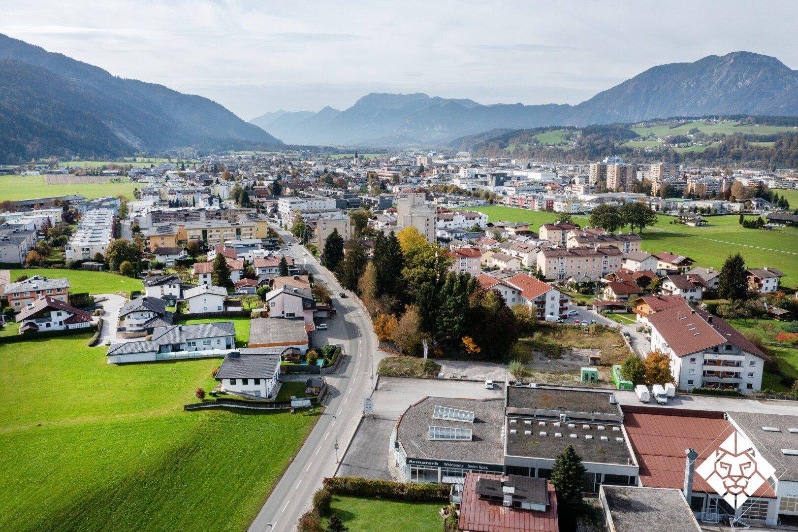 Weitläufige Luftaufnahme einer Stadt mit Wohngebäuden, Straßen und Bergen im Hintergrund.
