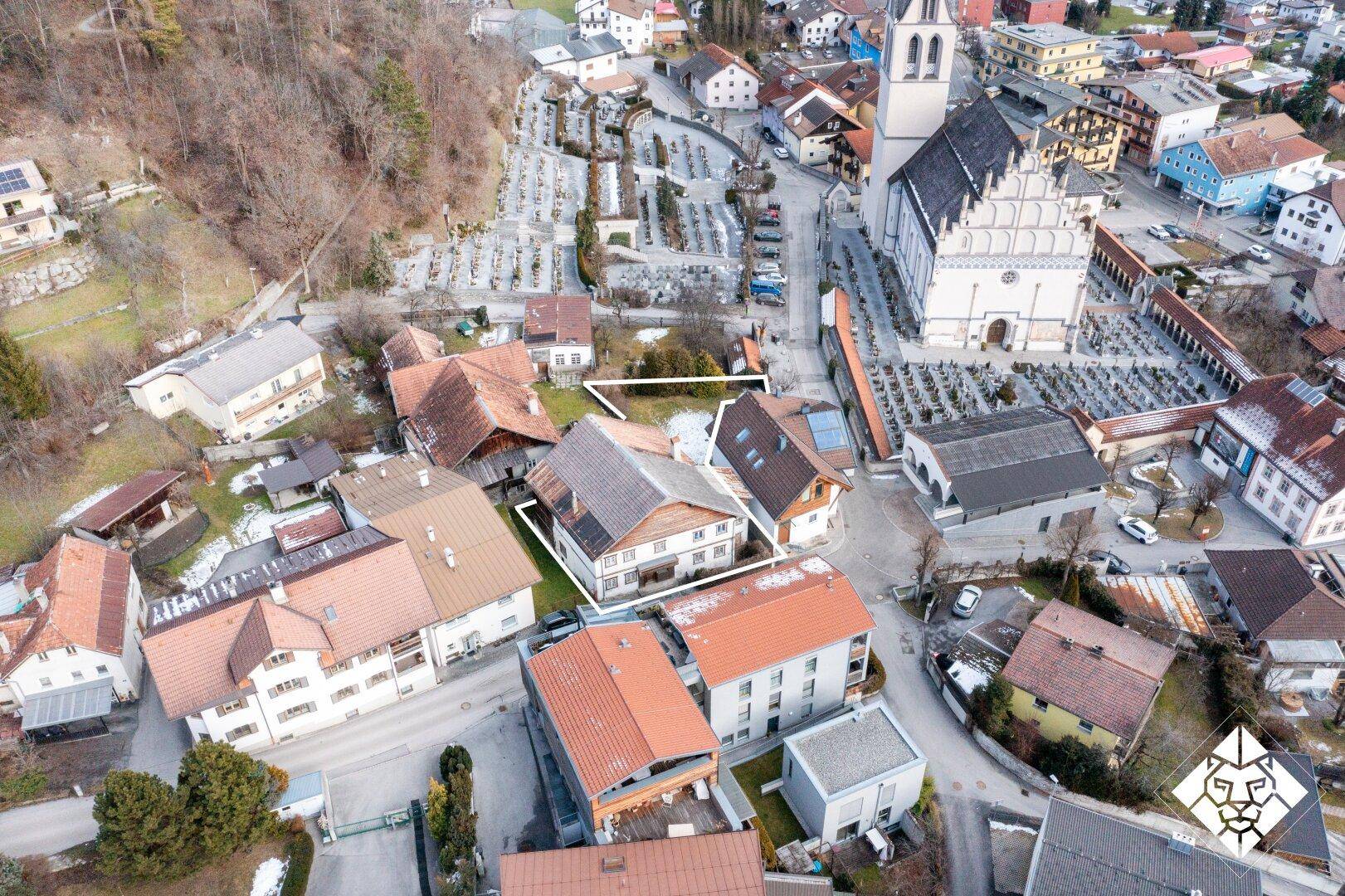 Detailreiche Luftaufnahme eines Wohnhauses in der Nähe einer Kirche und eines Friedhofs, mit Grundstücksgrenzen.