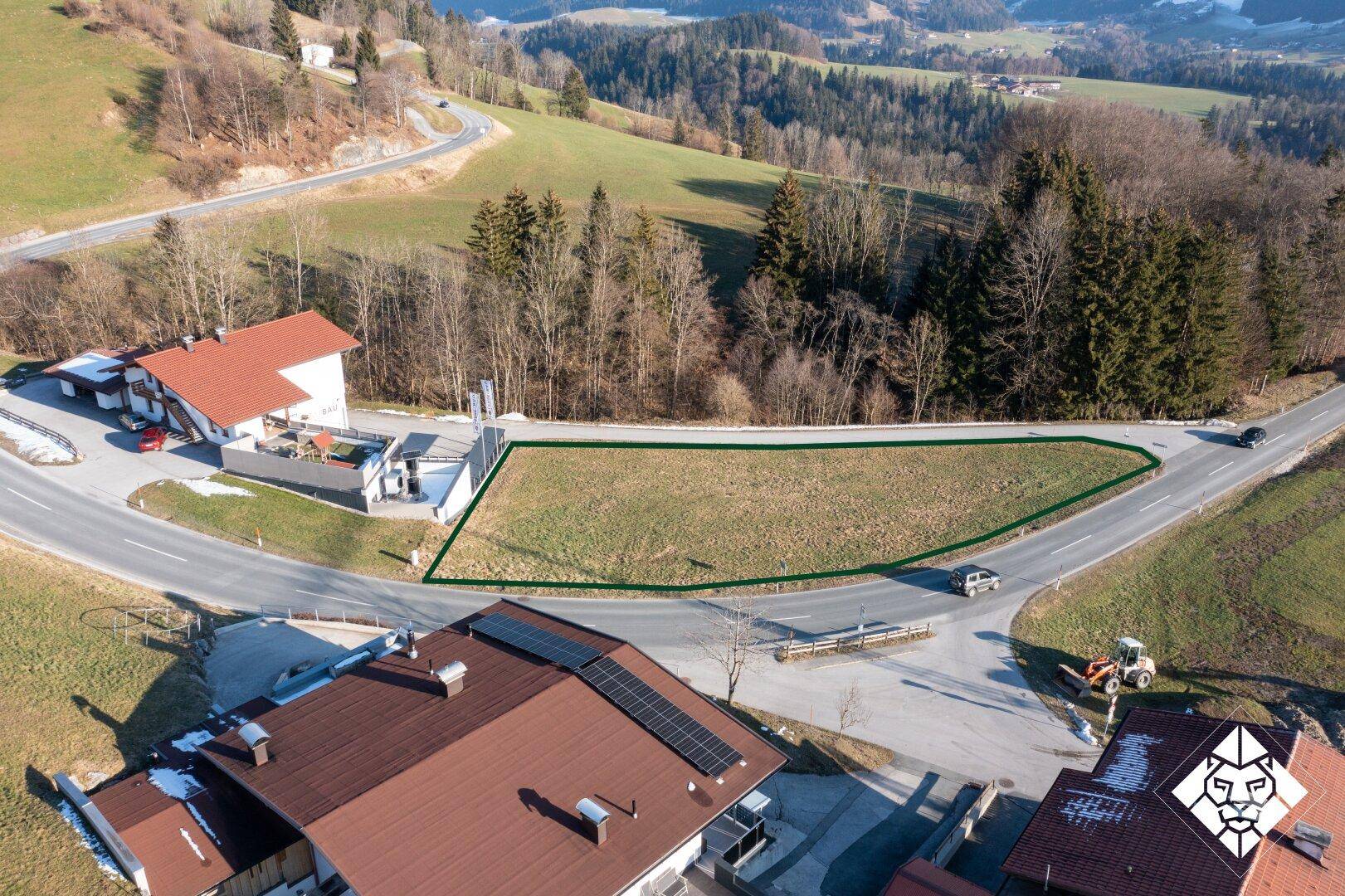 Übersicht des Baugrundstücks mit grüner Umrandung, umgeben von weiteren Häusern und einer Zufahrtsstraße.