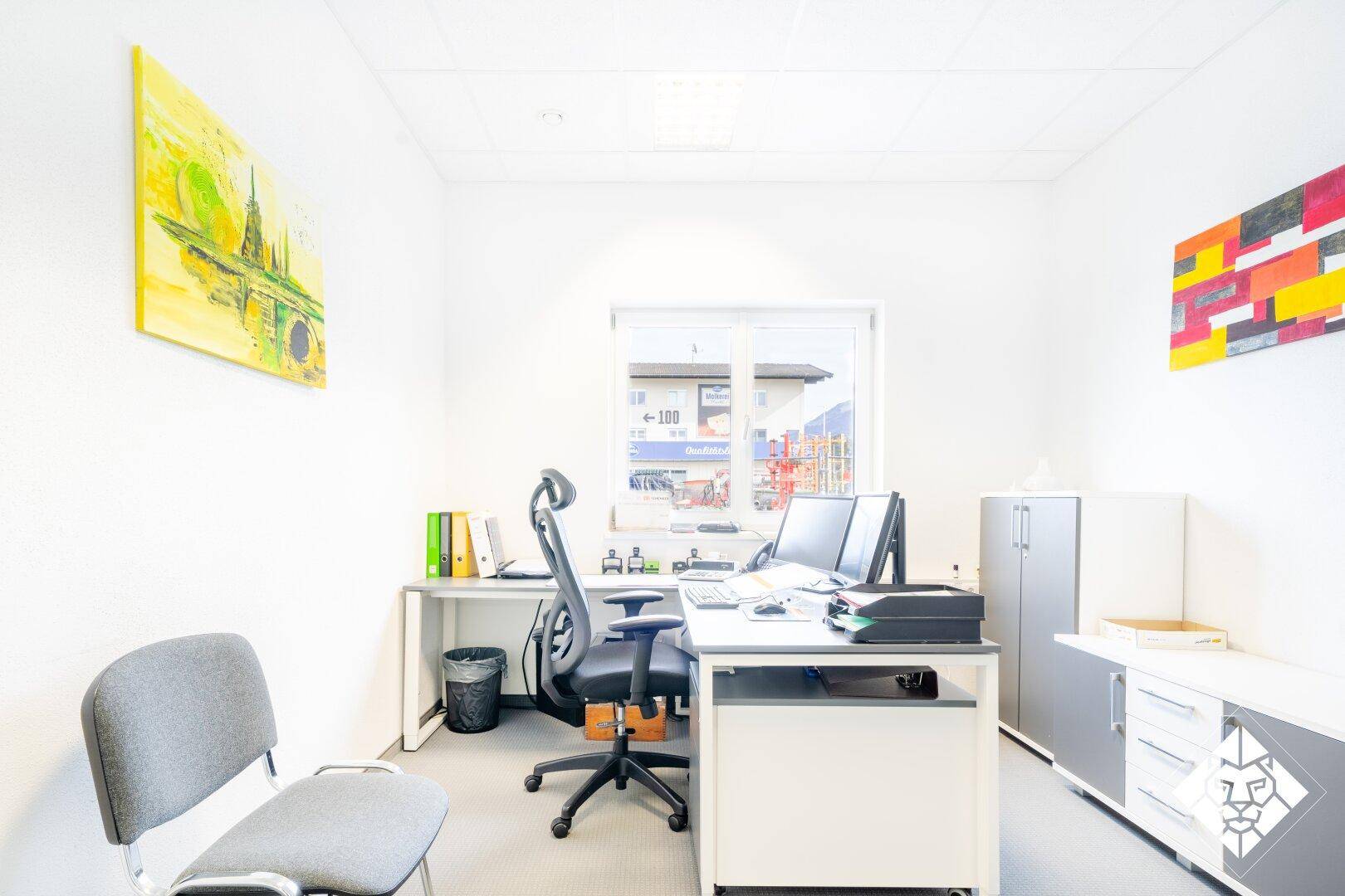 Funktionales Büro mit Schreibtisch, Bürostuhl und Stauraum, dekoriert mit farbigen Bildern.