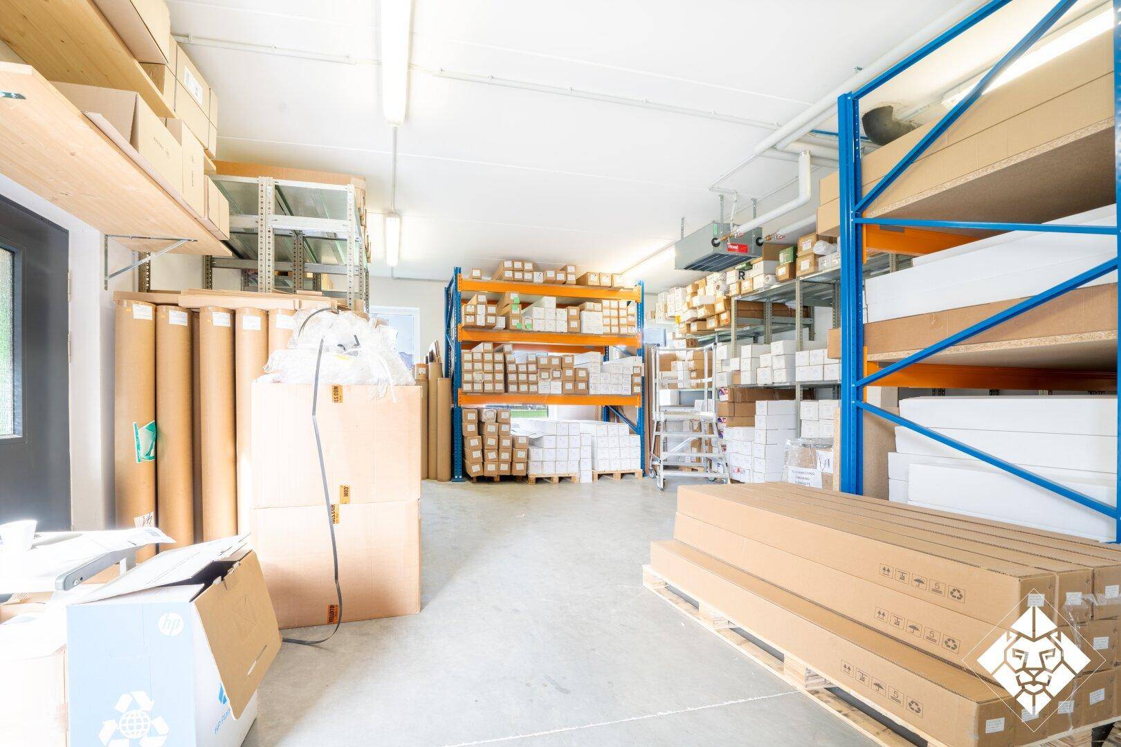 Lagerraum mit hohen Regalen, gefüllt mit Kartons und Verpackungsmaterialien.