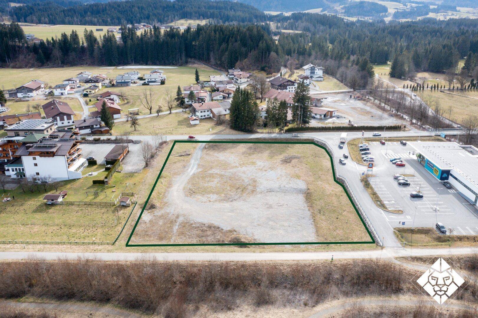 Übersichtsaufnahme eines umrandeten Baugrundstücks aus der Vogelperspektive, umgeben von einer Straße und Gebäuden.