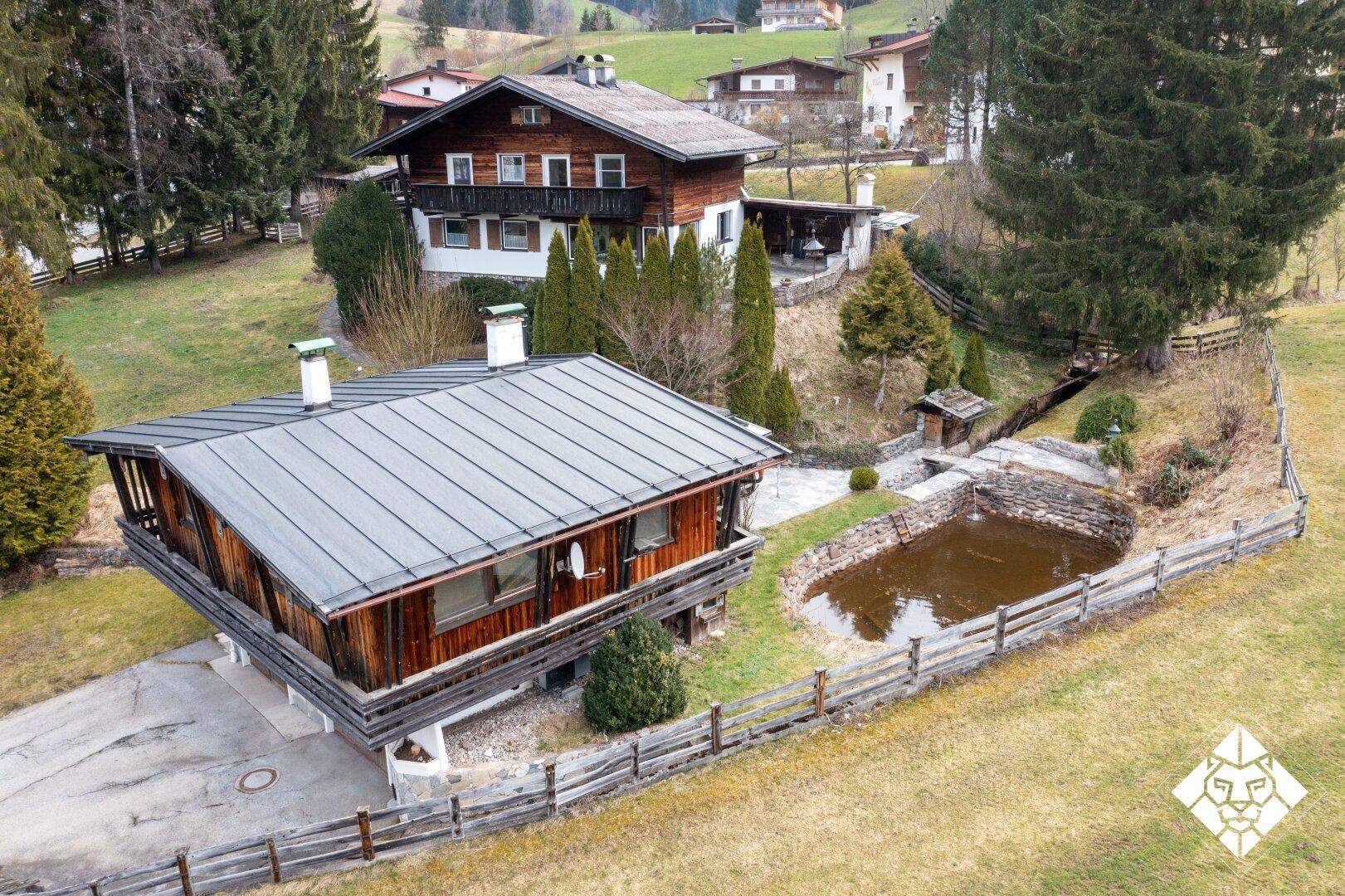 Luftaufnahme des Chalets mit Teich und umliegender grüner Landschaft.