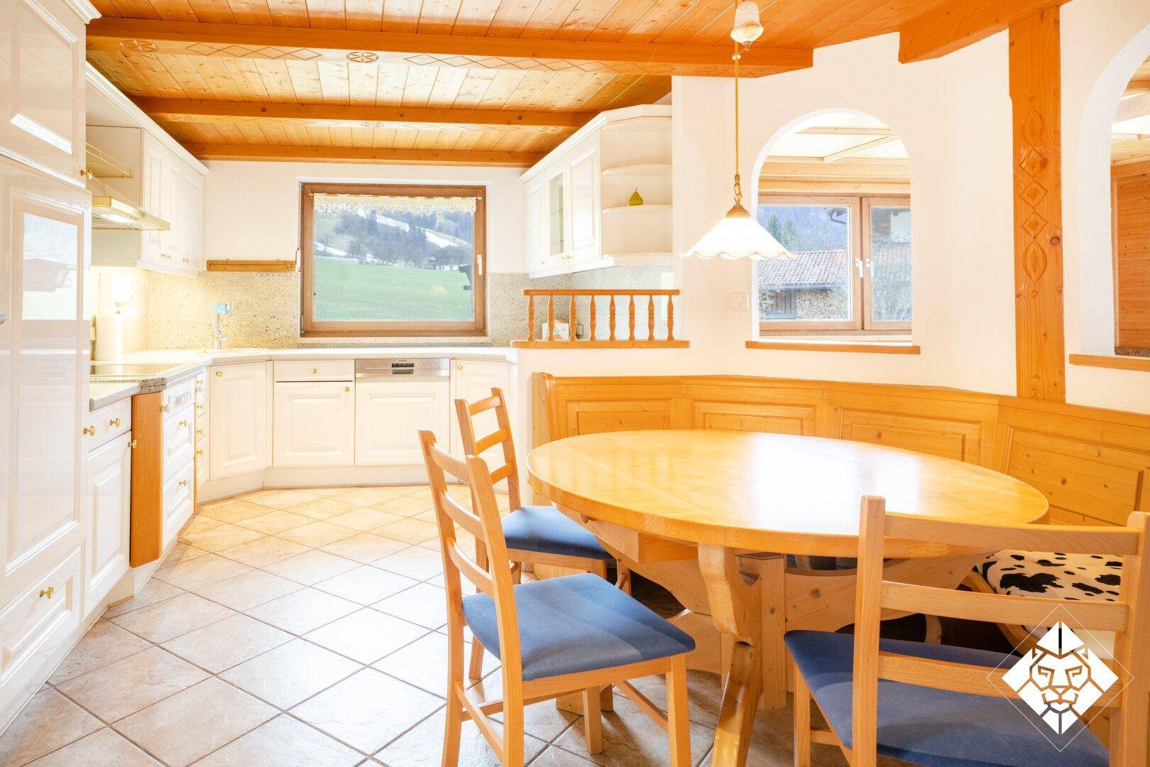 Gemütliche Wohnküche im Landhausstil mit Holzbalkendecke und Essbereich.