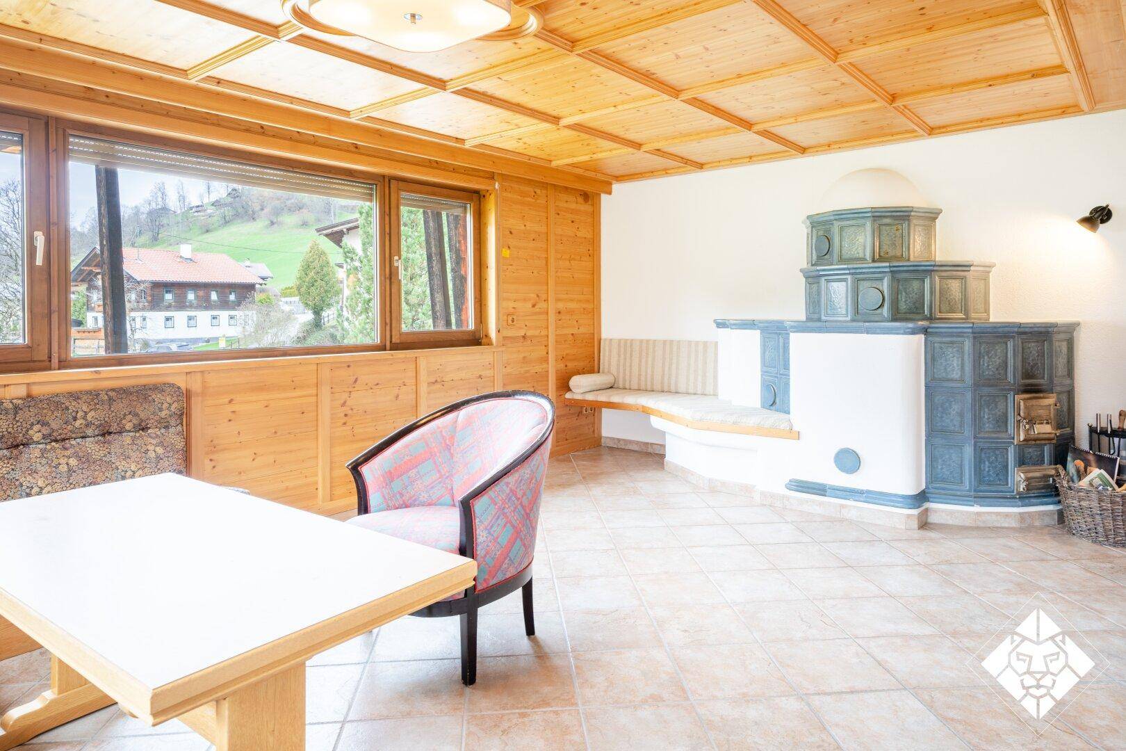 Gemütliches Wohnzimmer mit traditionellem Kachelofen und Holzvertäfelung.