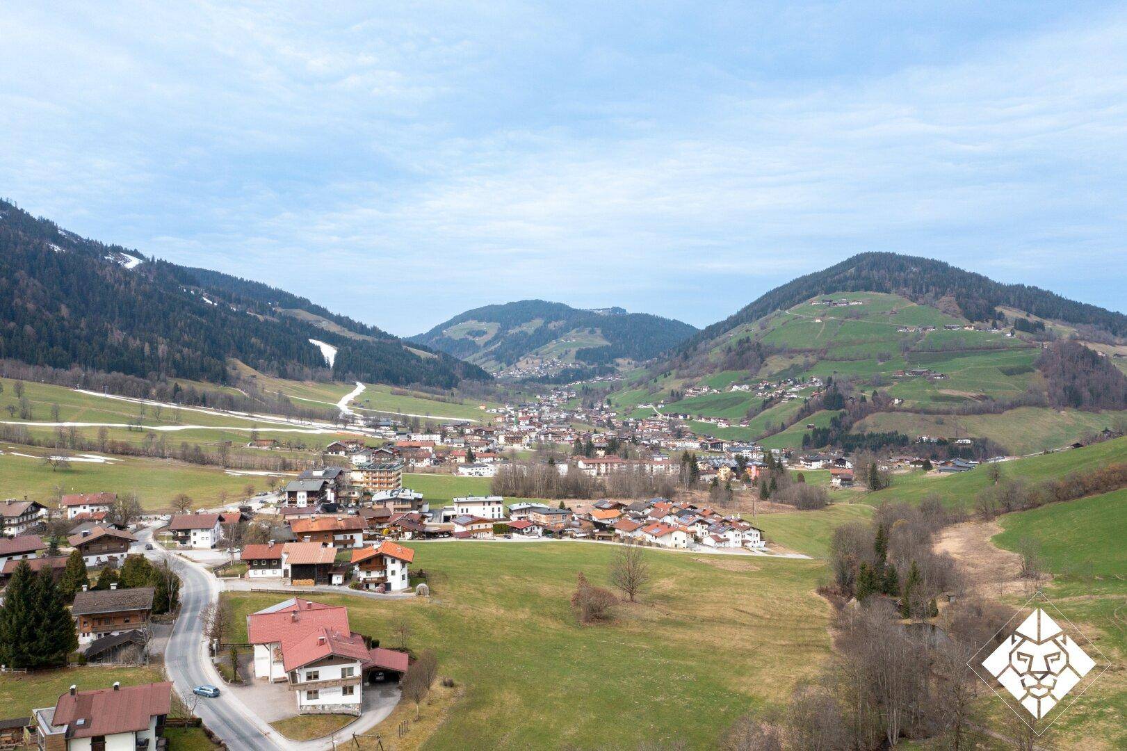 Panoramablick auf ein malerisches Dorf in einem grünen Tal mit Bergen.