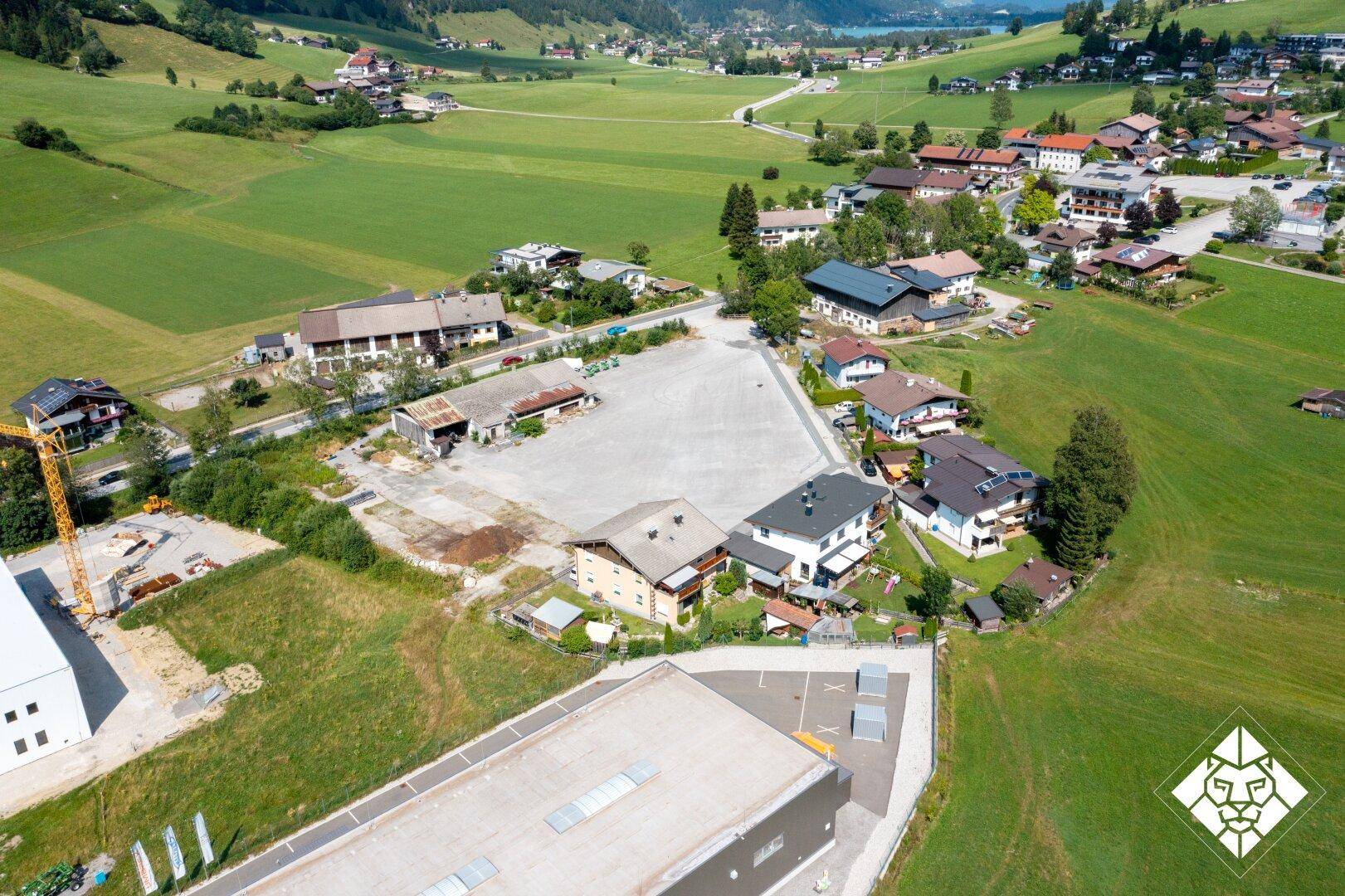 Panoramablick aus der Luft auf eine ländliche Gegend mit Häusern, Feldern und einem See in der Ferne.