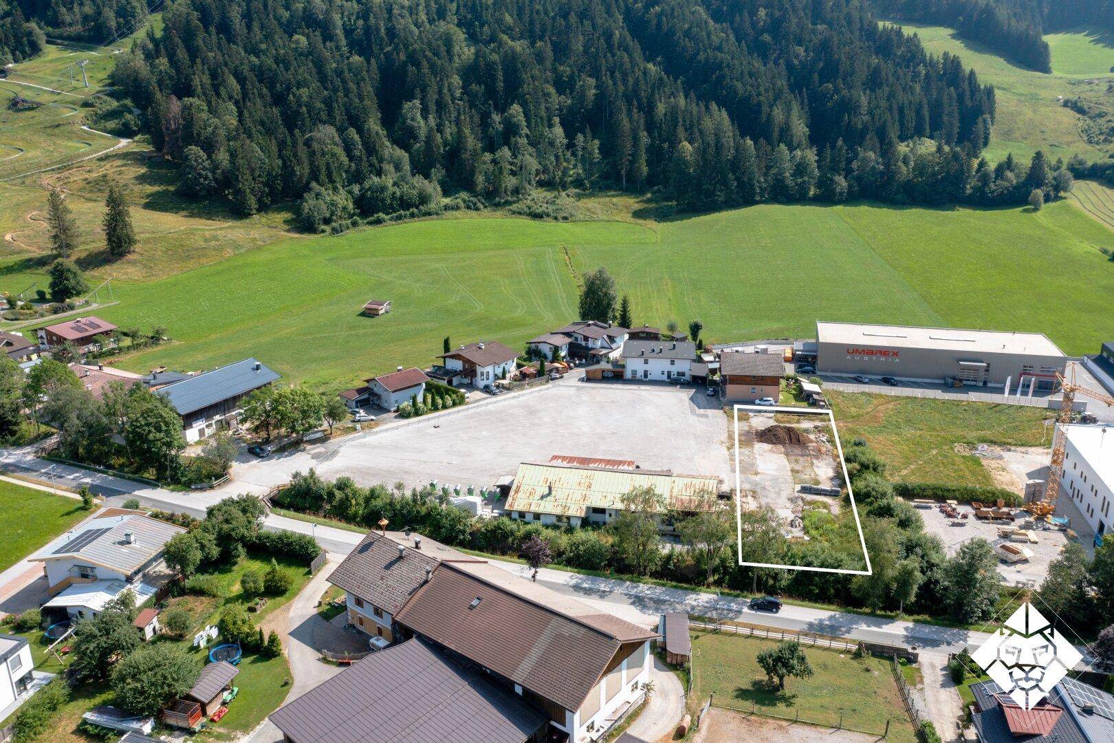 Panoramablick aus der Vogelperspektive auf eine ländliche Gegend mit Wald, Wiesen und einem markierten Grundstück.