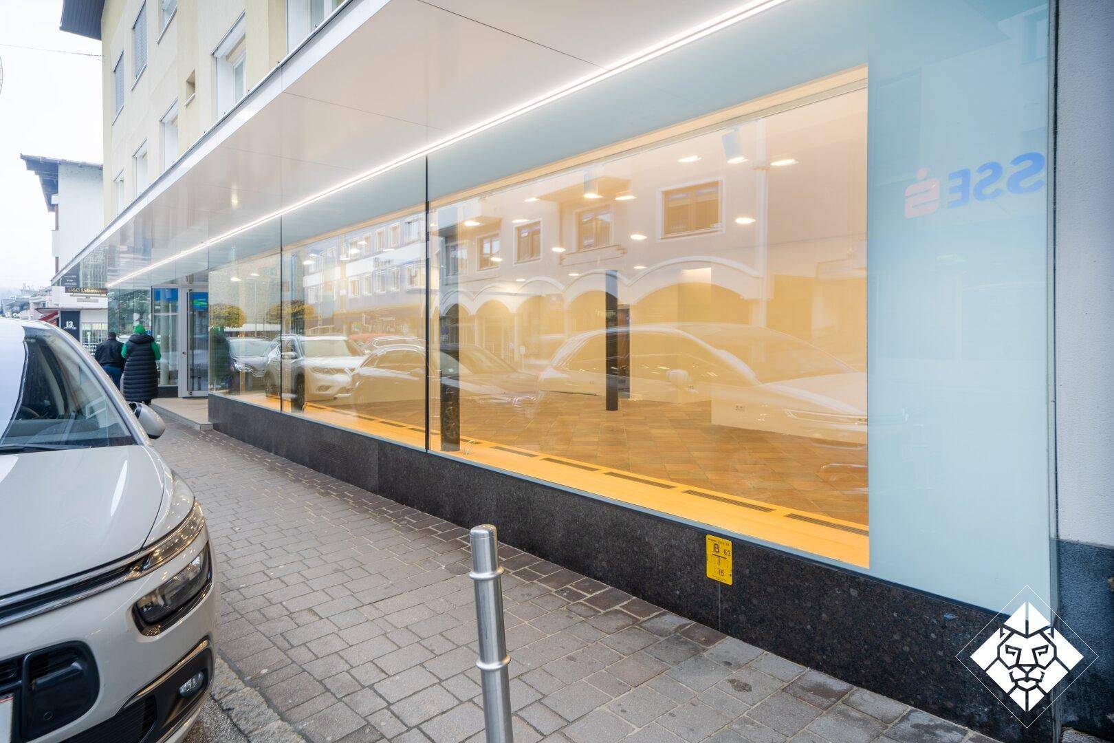 Detailansicht der modernen Glasfassade des Geschäftsraums mit Reflexionen der Umgebung.