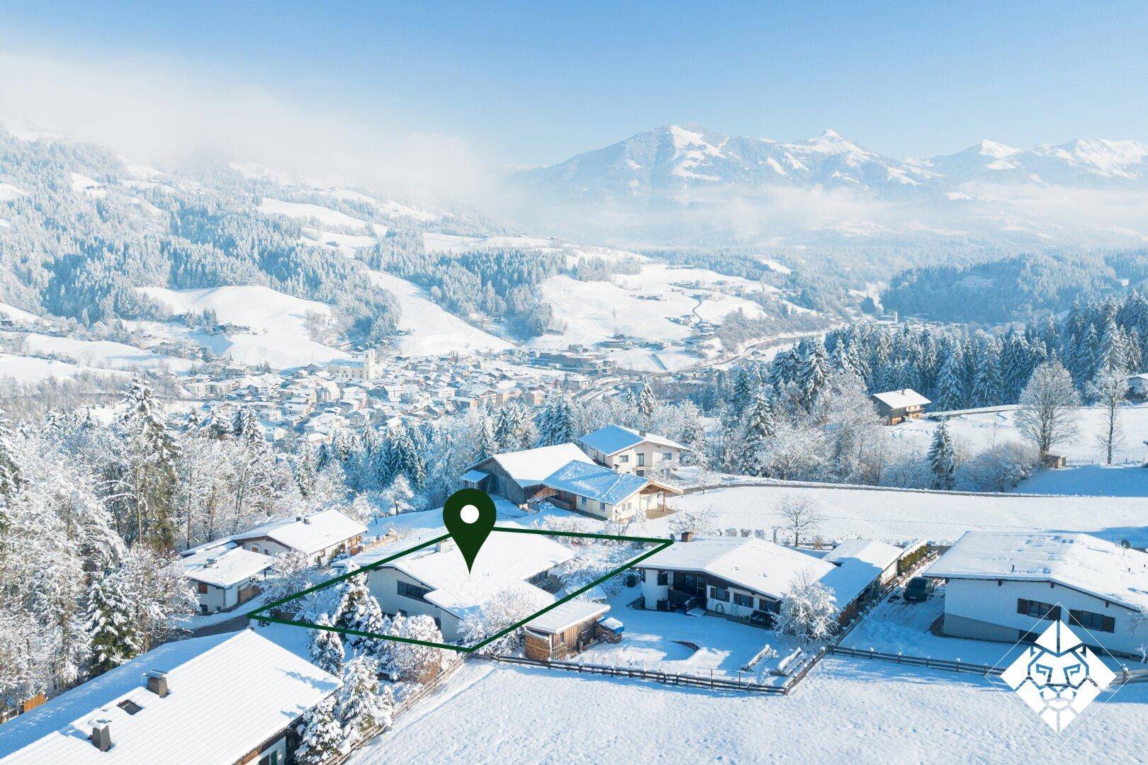 Verschneite Landschaft mit markiertem Grundstück und Bergblick, umgeben von weiteren Häusern.