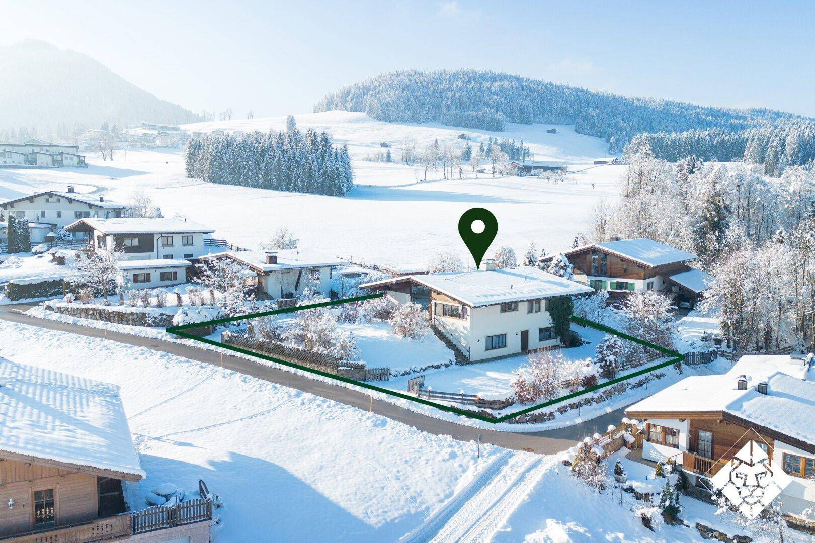 Luftaufnahme eines Hauses im Schnee mit markiertem Grundstück und umliegender Winterlandschaft.