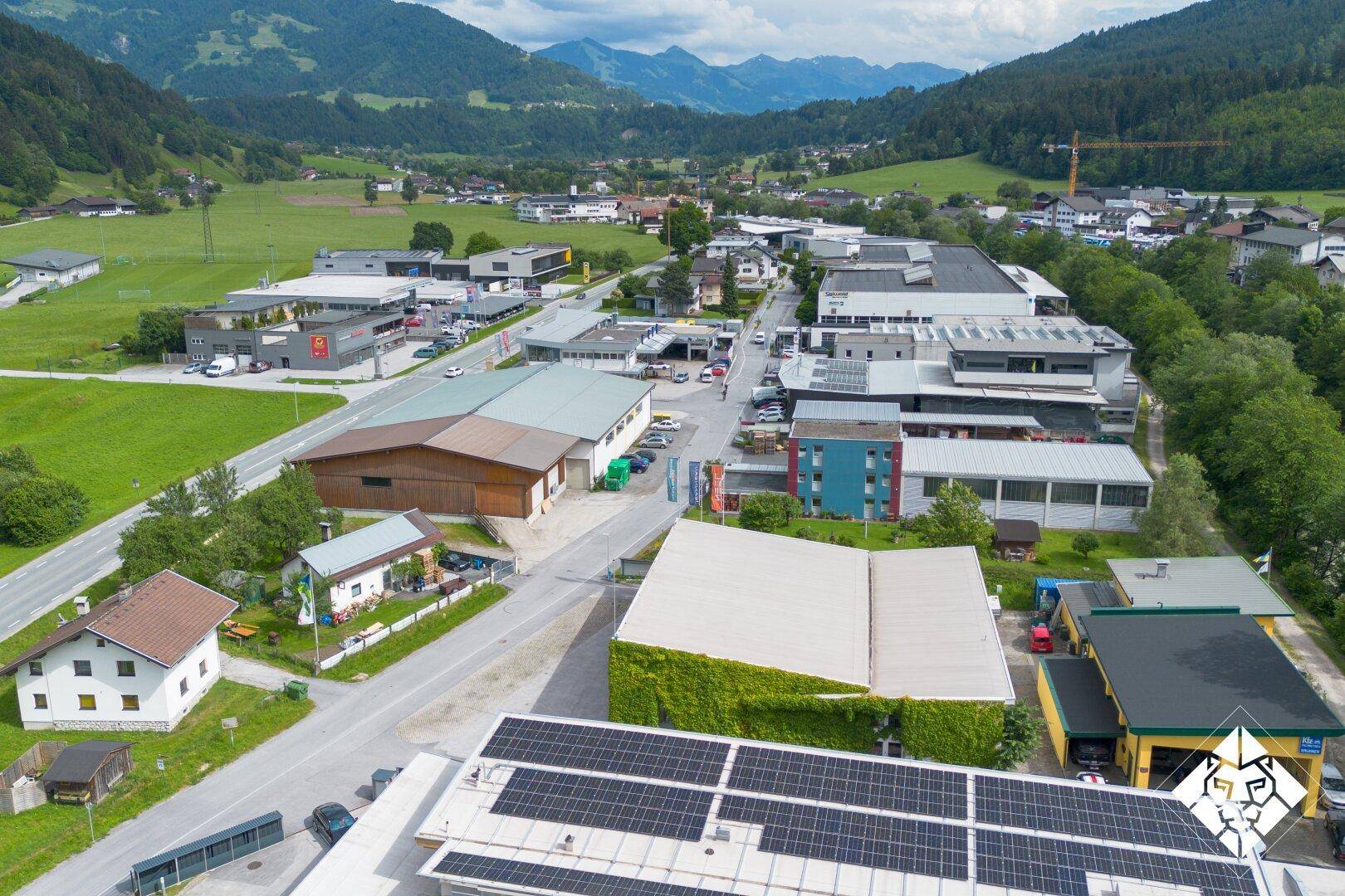 Überblick über ein Gewerbegebiet mit Wohnhäusern und einem Gebäude mit Photovoltaikanlage auf dem Dach.