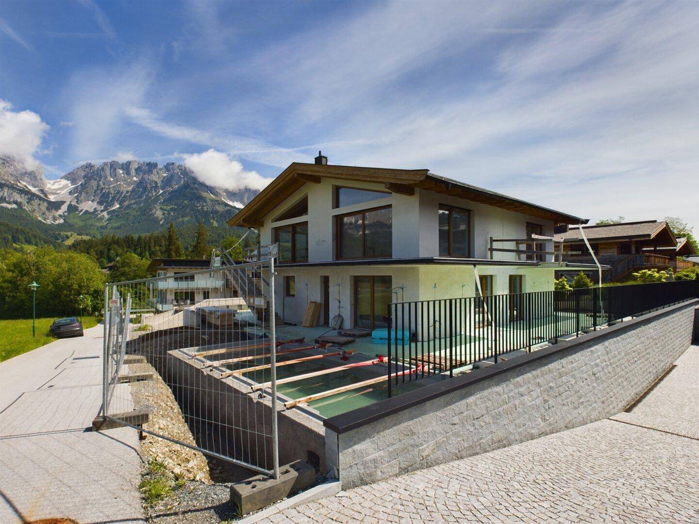 Neubau eines Hauses in alpiner Umgebung mit Bergblick und Baustelle im Vordergrund.