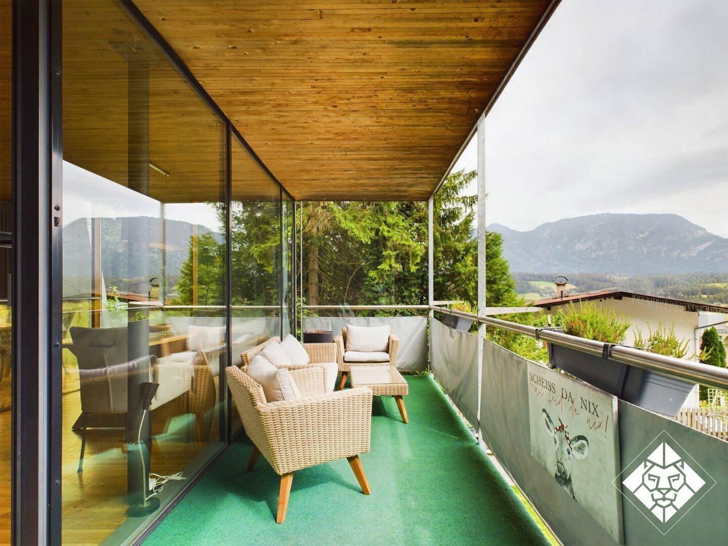 Geräumiger Balkon mit Rattanmöbeln und Panoramablick auf die umliegende Berglandschaft.