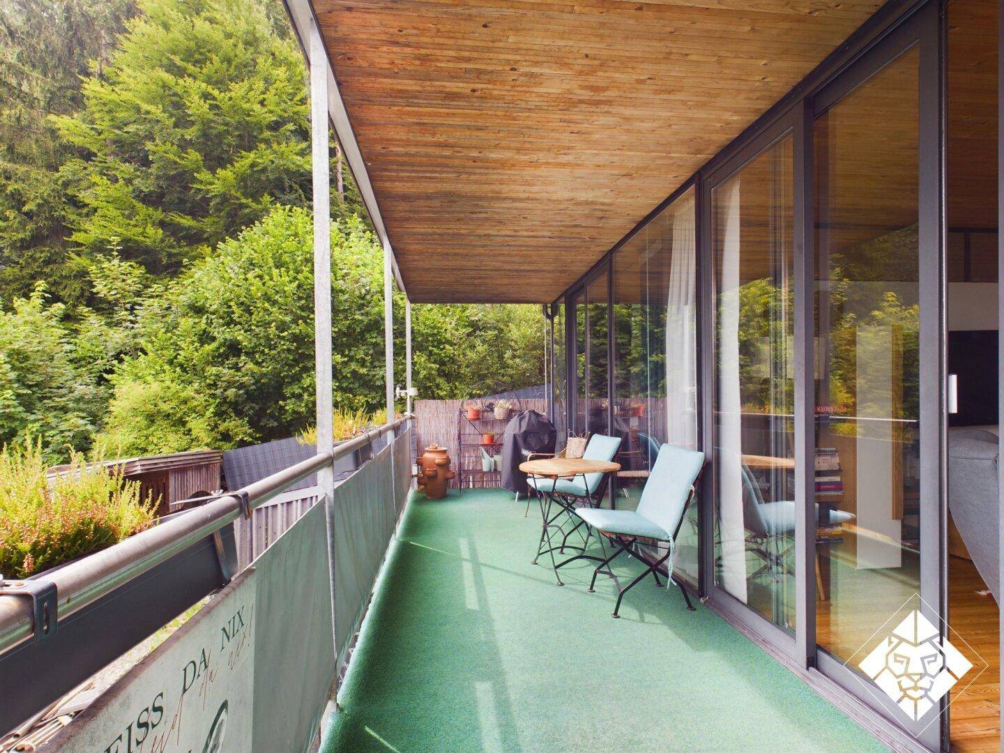 Überdachter Balkon mit Sitzgelegenheiten, Pflanzen und direktem Zugang zu den Innenräumen.