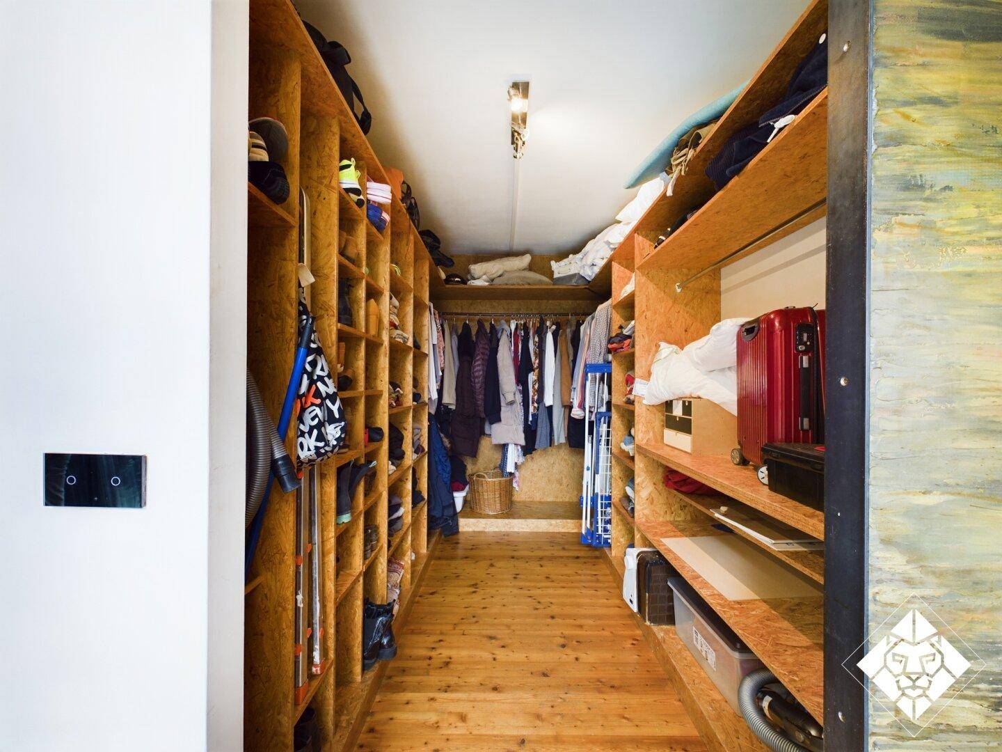 Geräumiger begehbarer Kleiderschrank mit maßgefertigten Holzregalen und viel Stauraum.