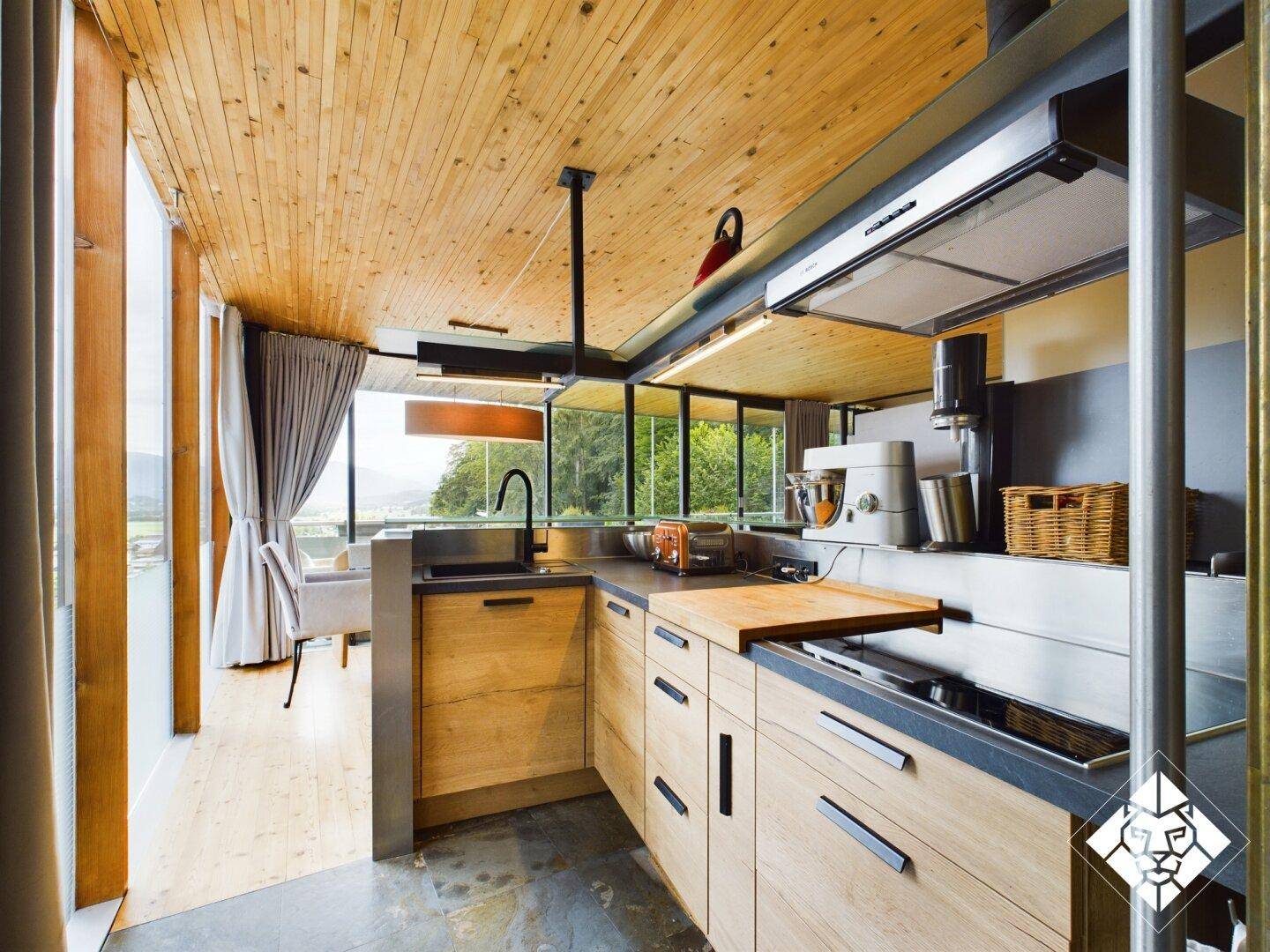 Funktionale Küche mit Holzelementen, modernen Geräten und Arbeitsflächen aus dunklem Stein.