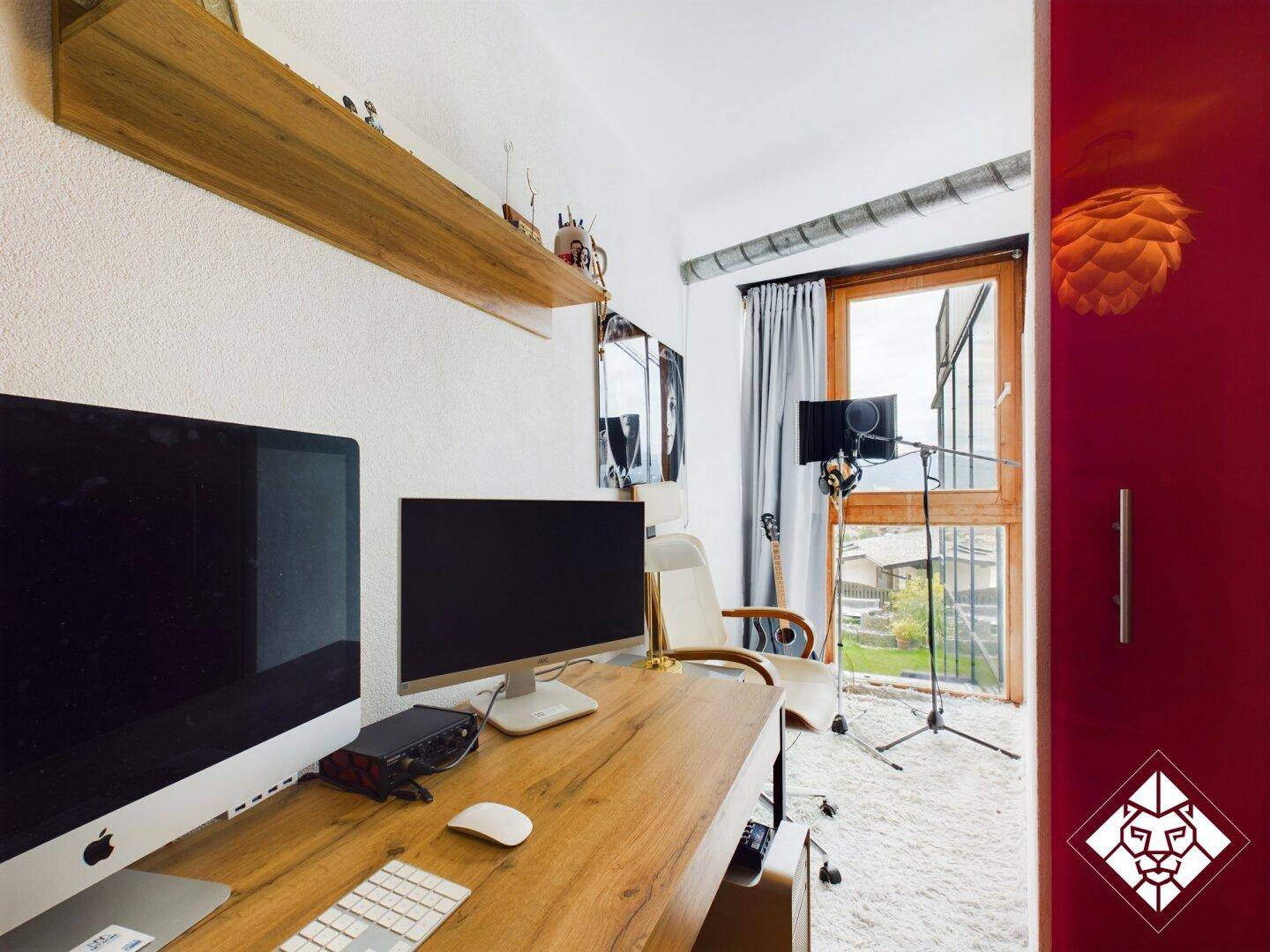 Modernes Arbeitszimmer mit zwei Monitoren, Holztisch und Blick ins Grüne durch das Fenster.
