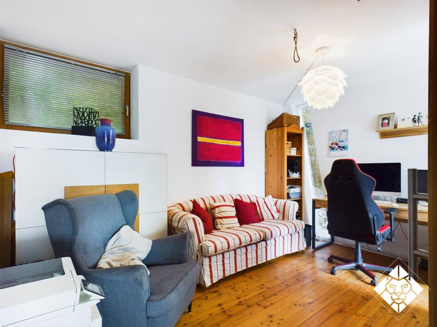 Vielseitiger Raum mit Schreibtisch, Sofa und Fenster, ideal als Arbeits- oder Gästezimmer.